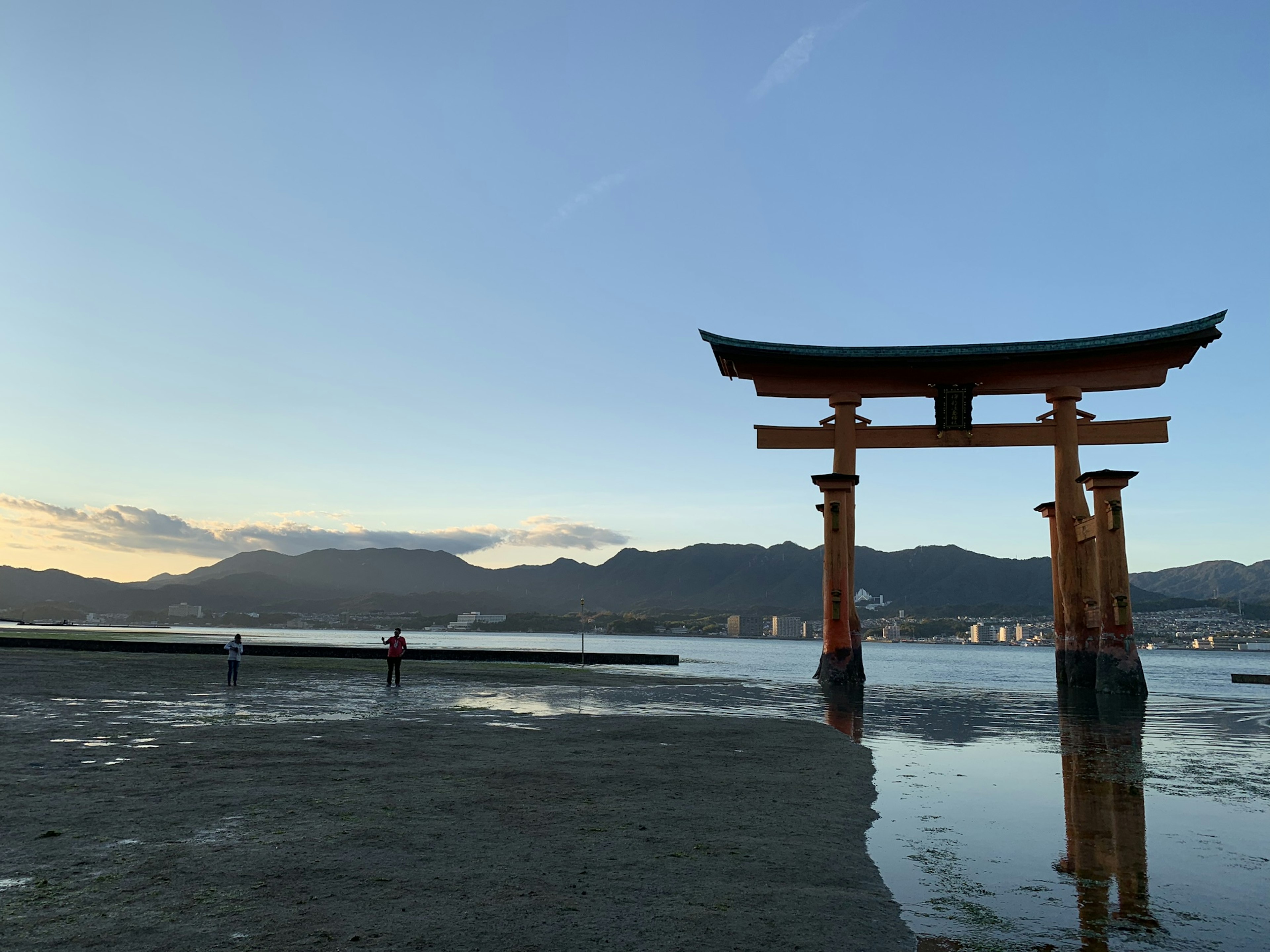 Torii yang berdiri di laut dengan latar belakang matahari terbenam yang indah