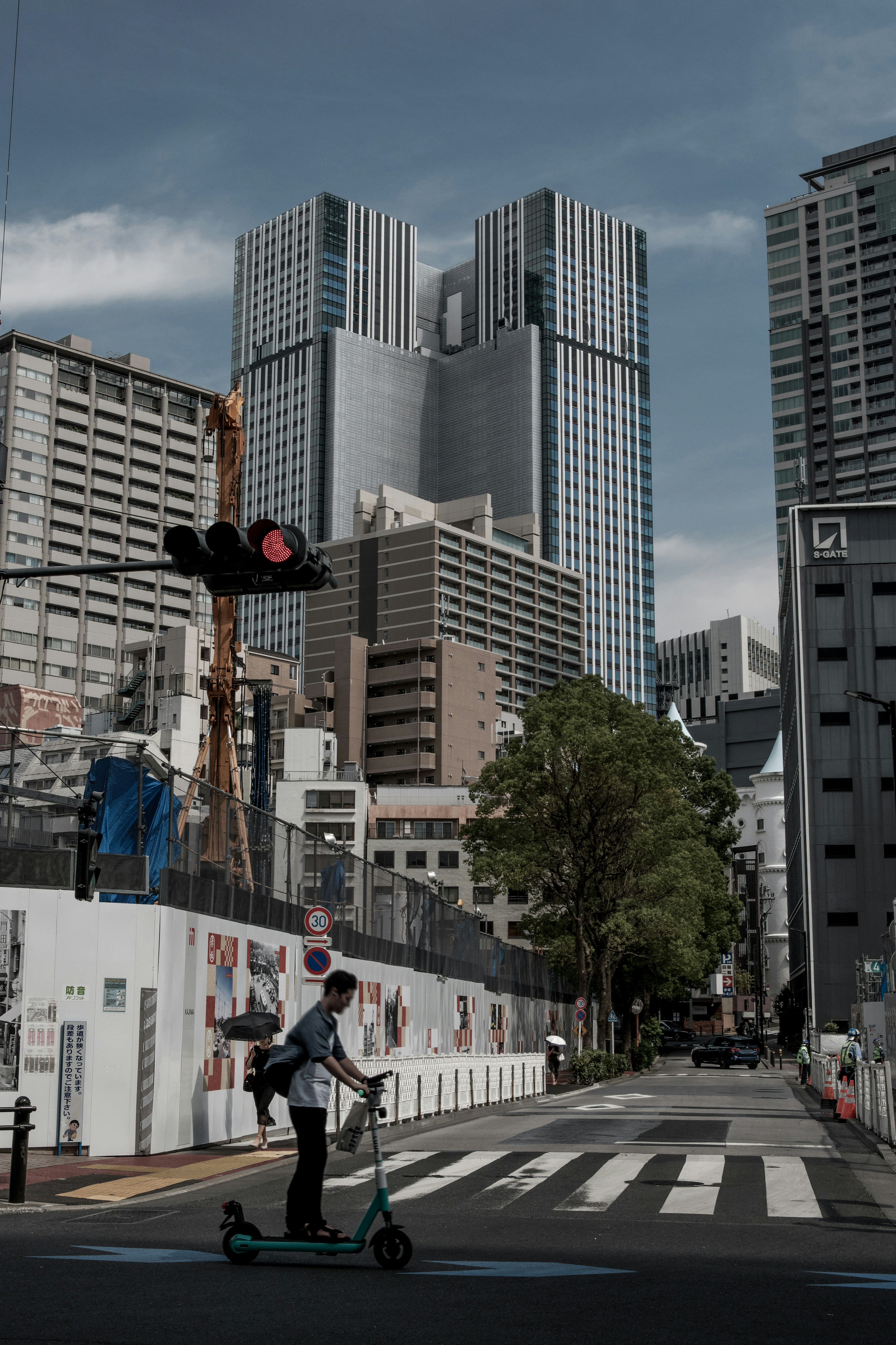 Una persona montando un patinete eléctrico en una intersección urbana con rascacielos