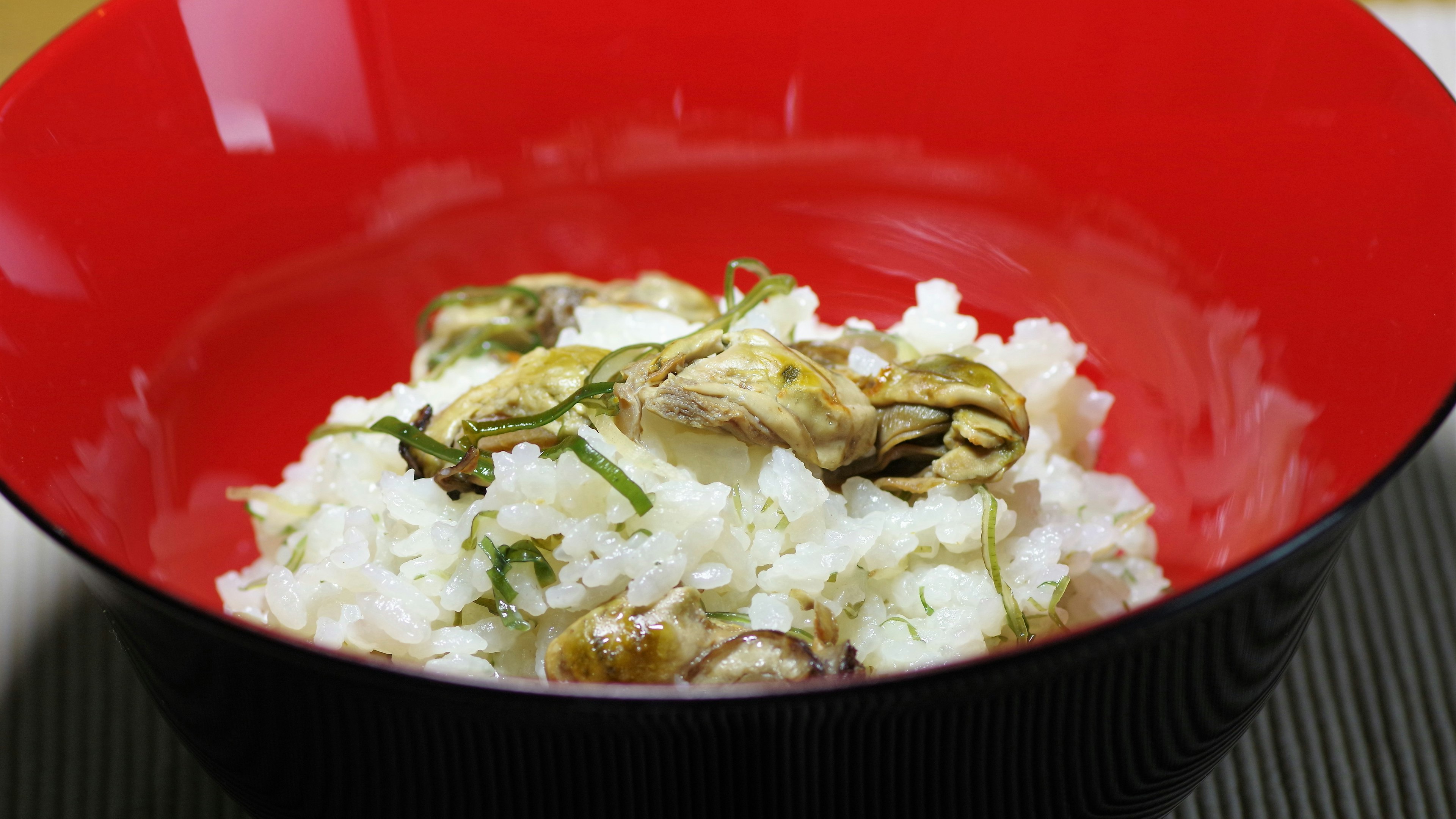 White rice served in a red bowl with herb toppings