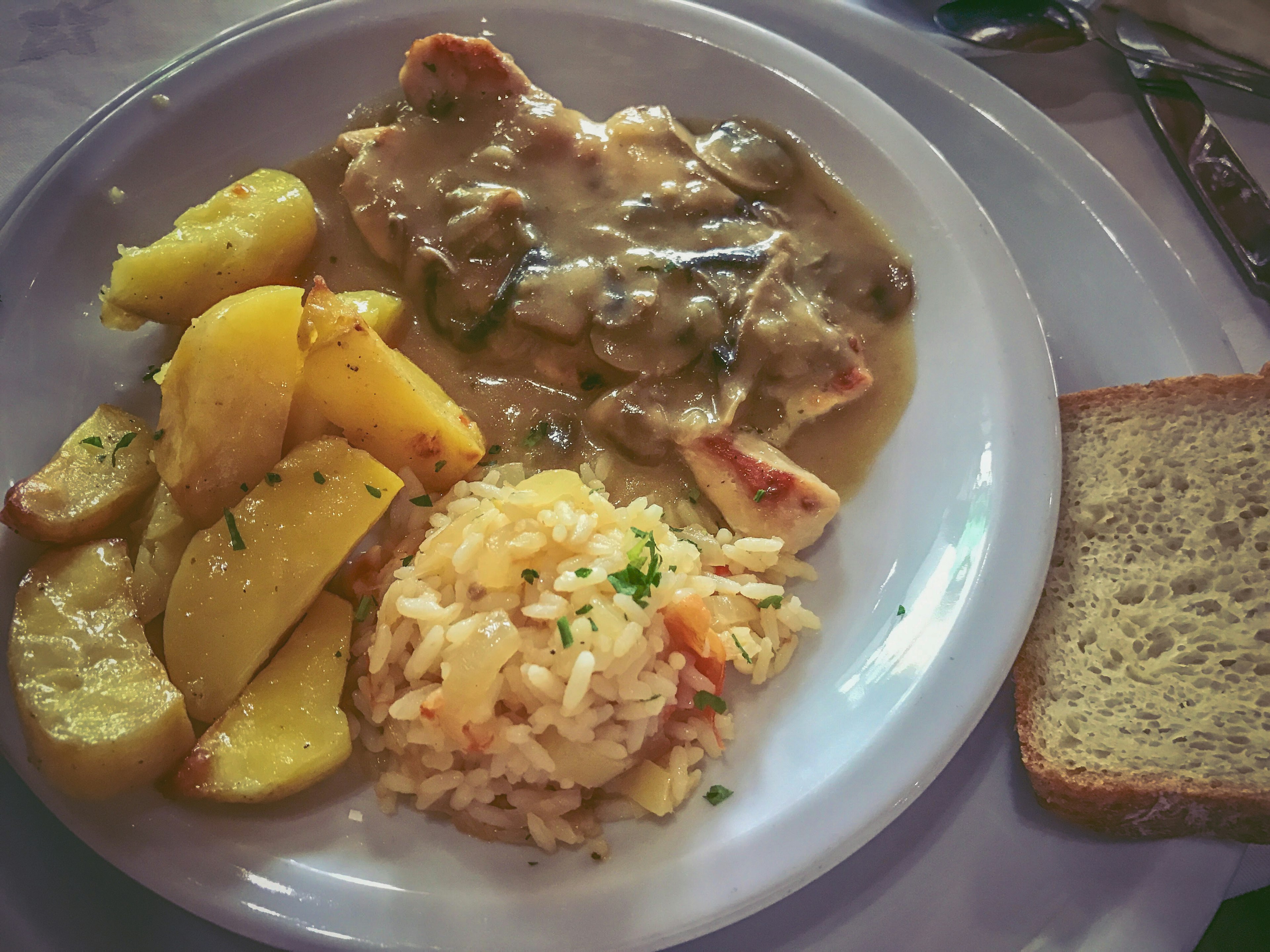 Assiette de nourriture avec poulet dans une sauce gravy avec des champignons pommes de terre risotto et pain