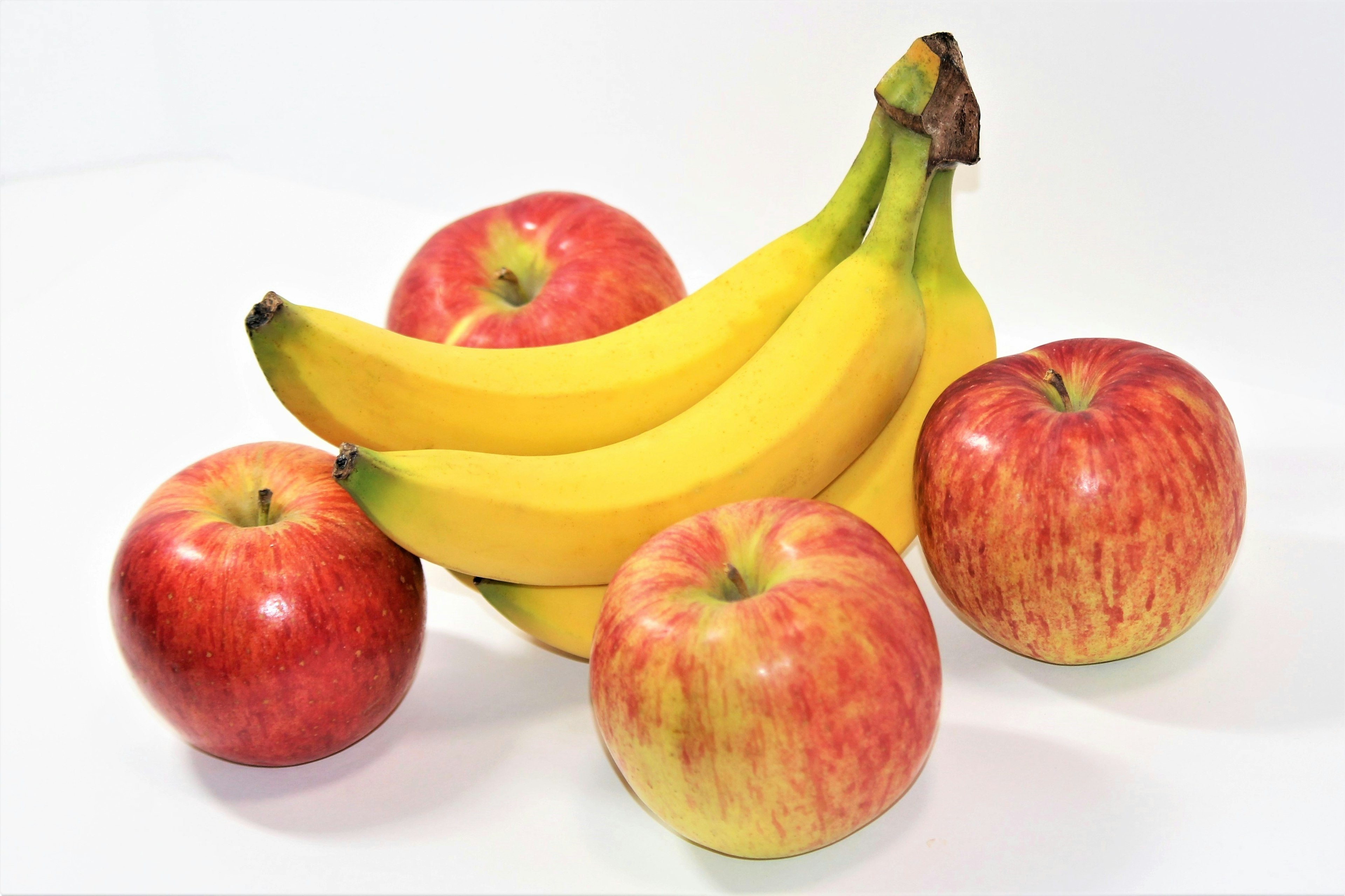 A colorful arrangement of bananas and apples on a white background