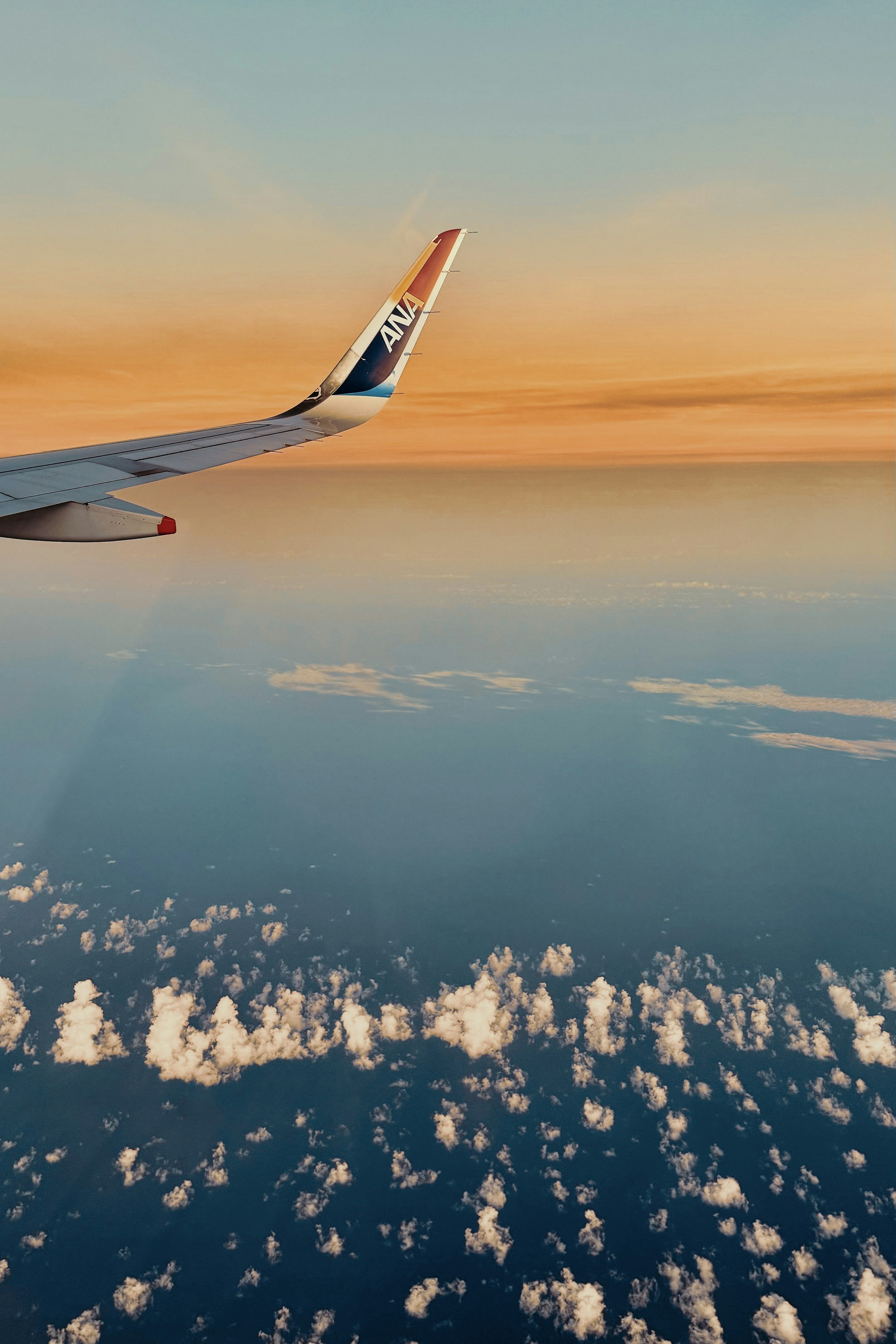 Airplane wing over clouds during a beautiful sunset