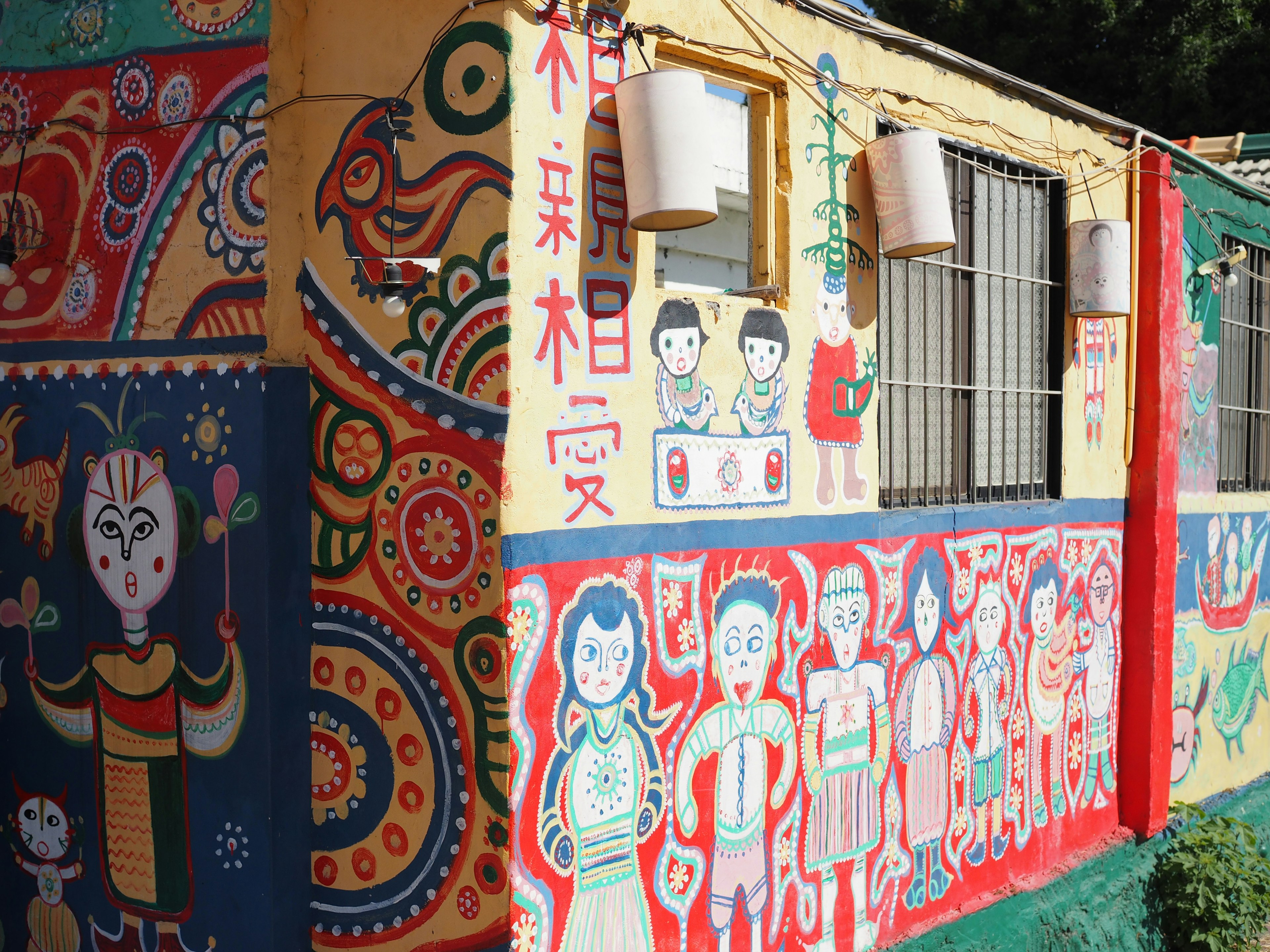 Colorful exterior of a building adorned with murals featuring diverse characters and patterns