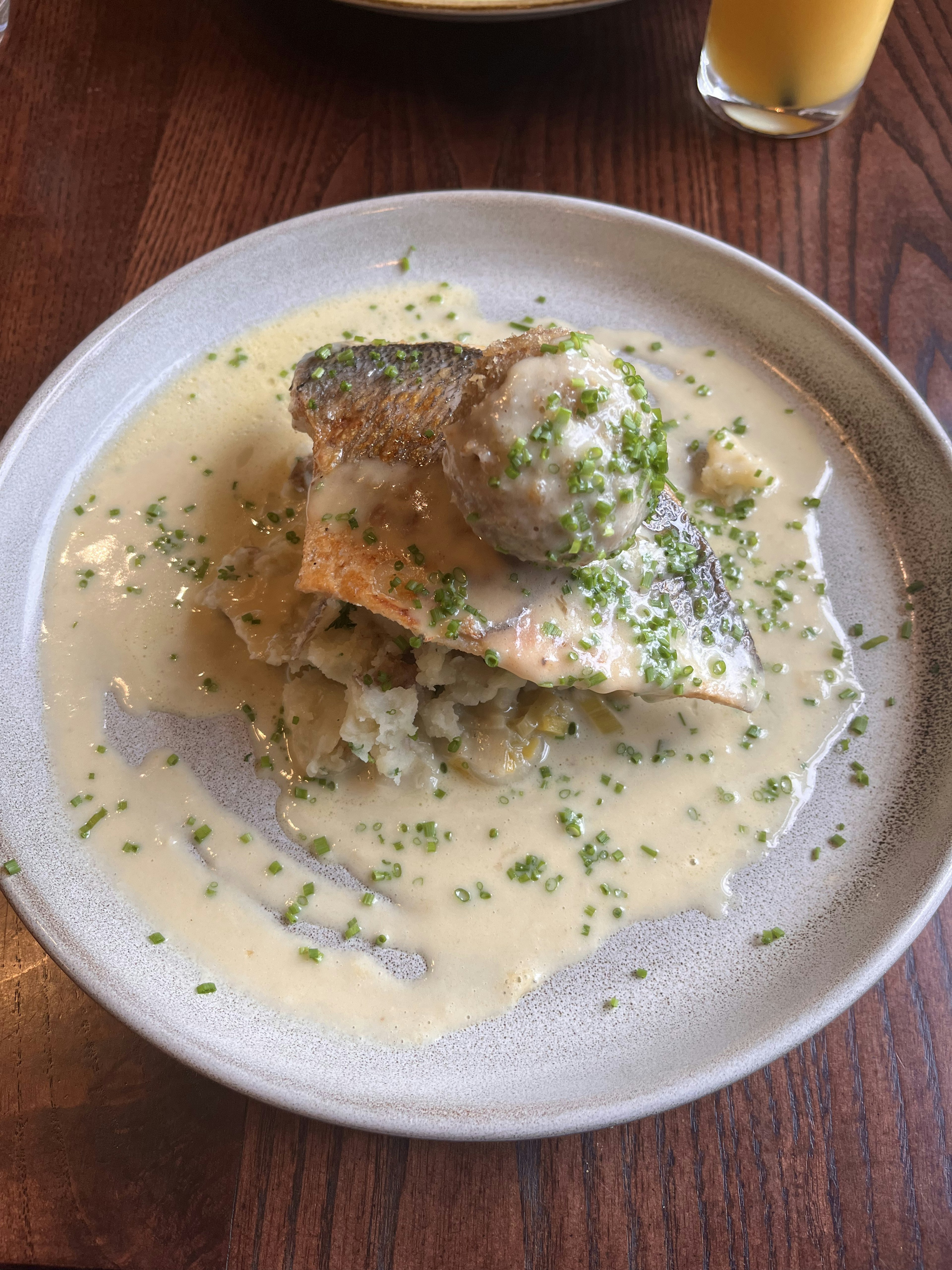 Un plat avec du saumon dans une sauce crémeuse garni d'herbes