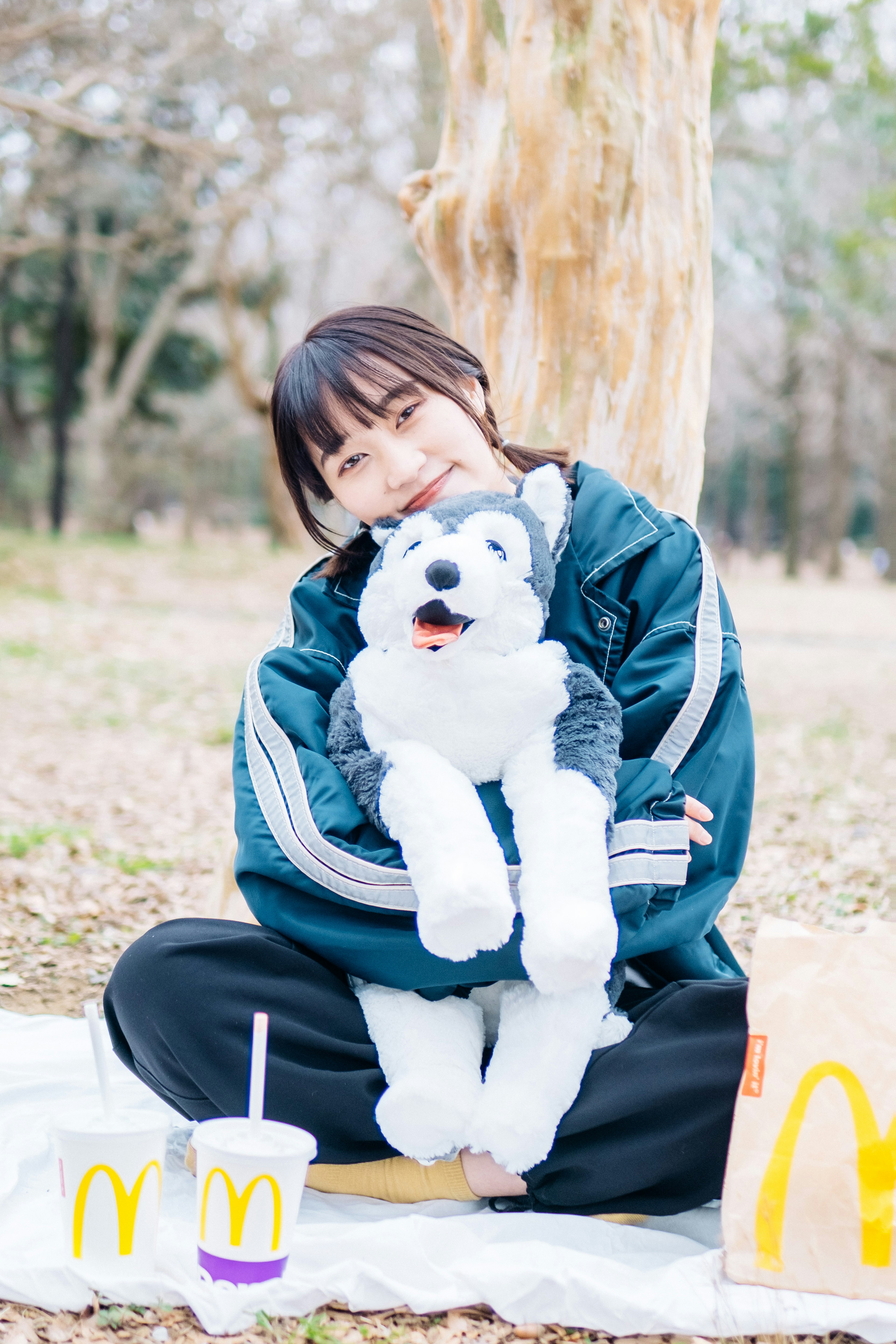 A girl hugging a stuffed husky in a park