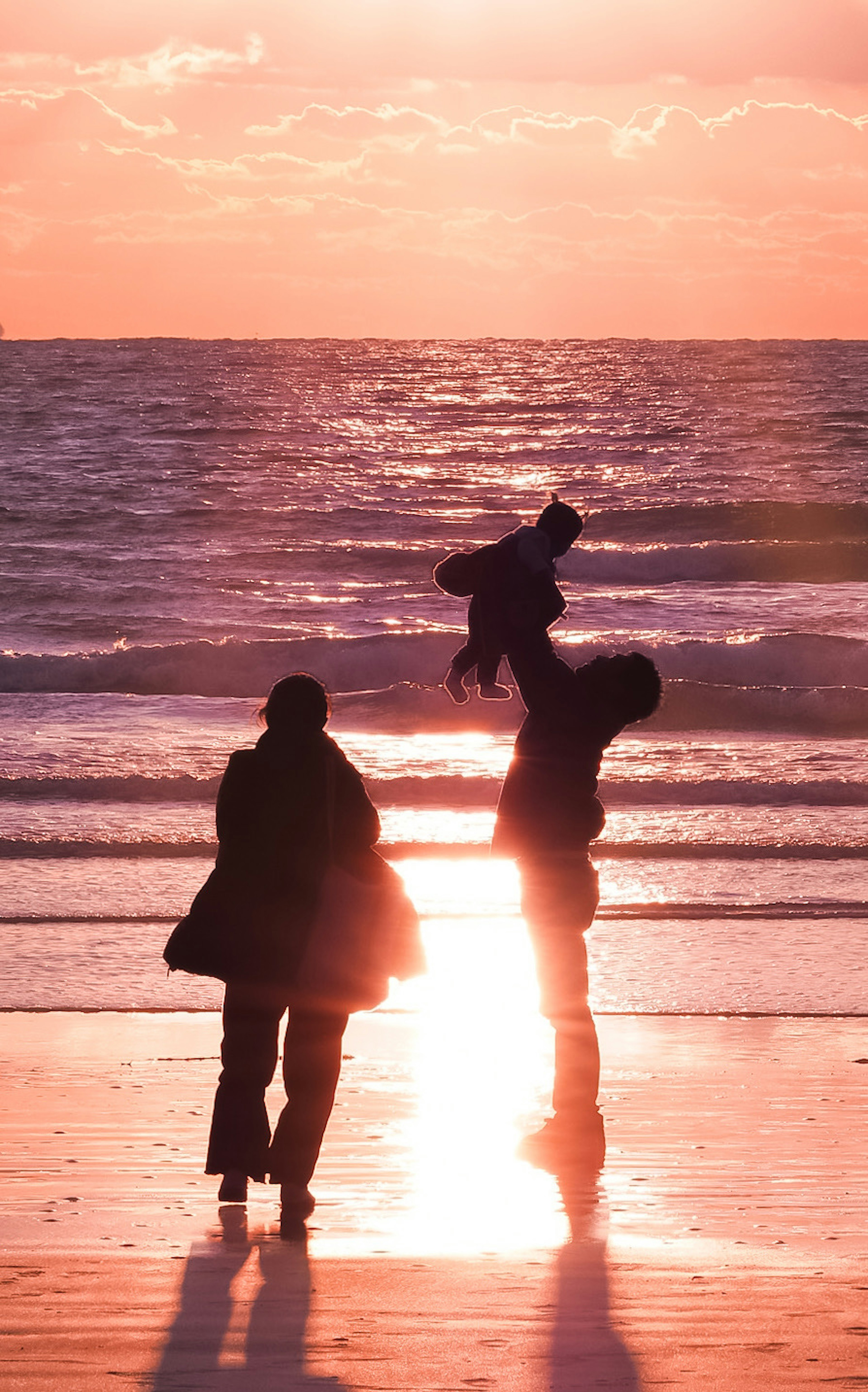 Silhouette of a family playing on the beach at sunset