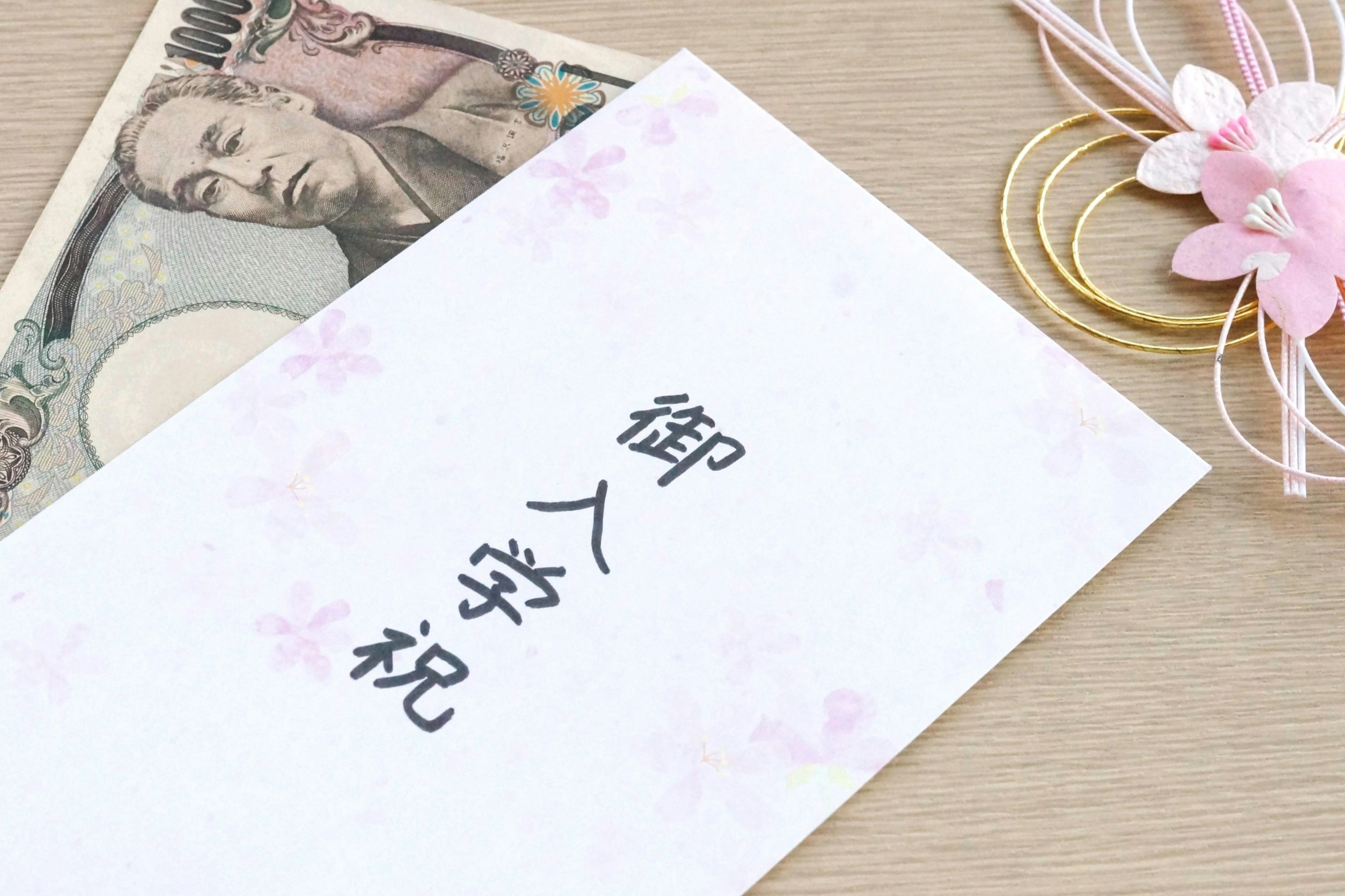 A white envelope with cherry blossom patterns featuring the text for a congratulatory gift for school entrance