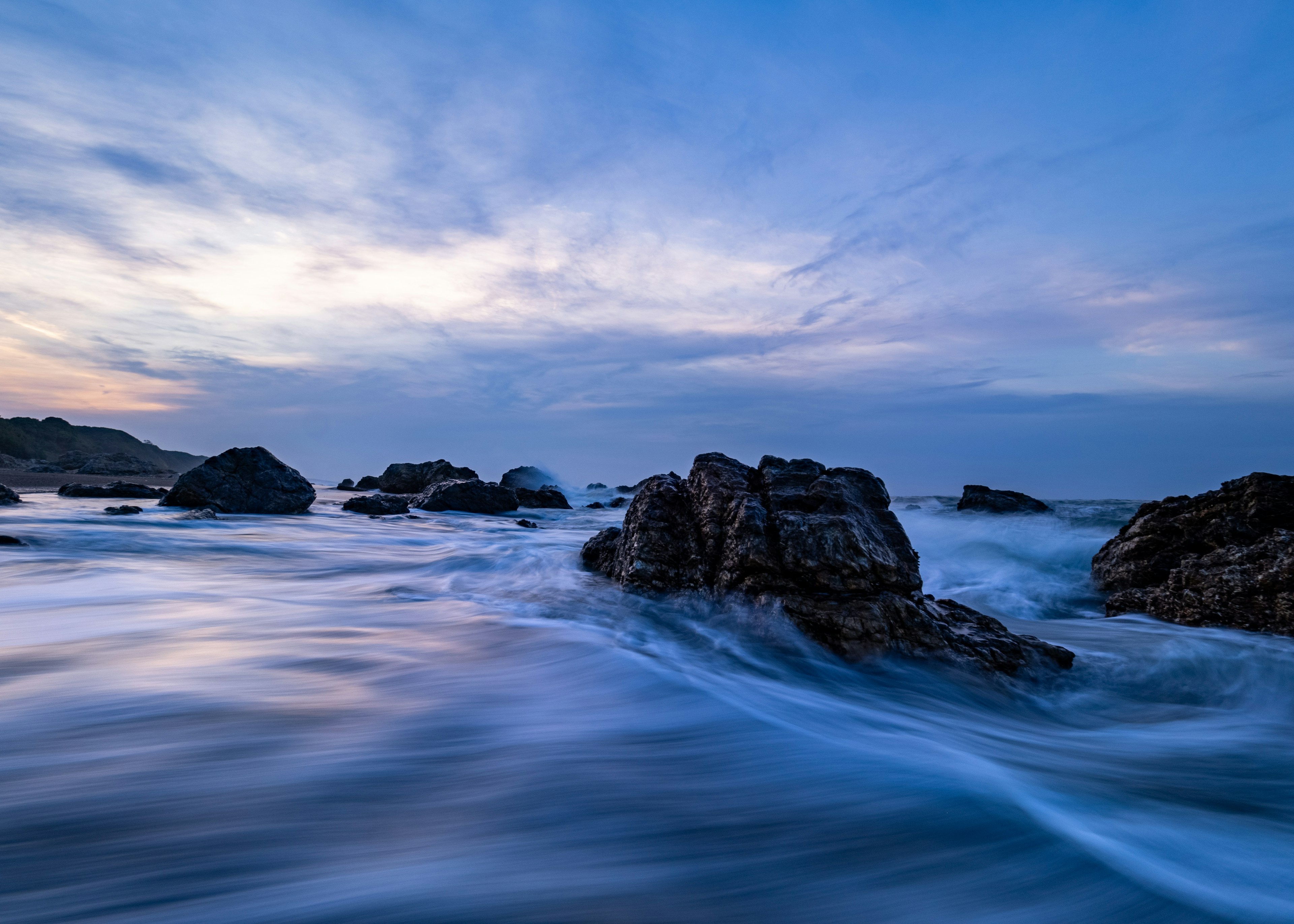 Paisaje marino sereno con formaciones rocosas cielo azul tranquilo y olas fluyentes