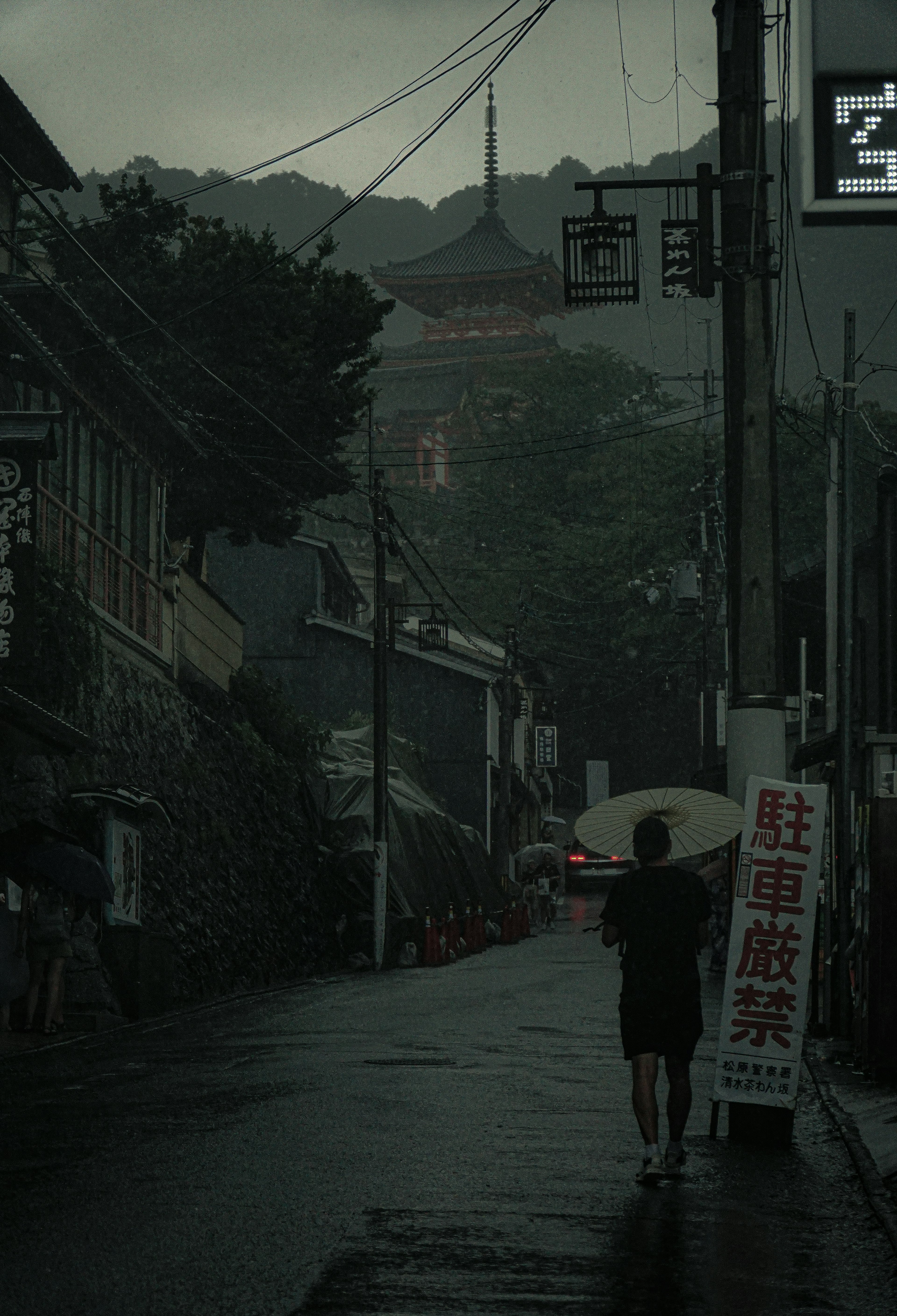 어두운 거리에서 오래된 건물 사이를 우산을 쓰고 걷는 사람