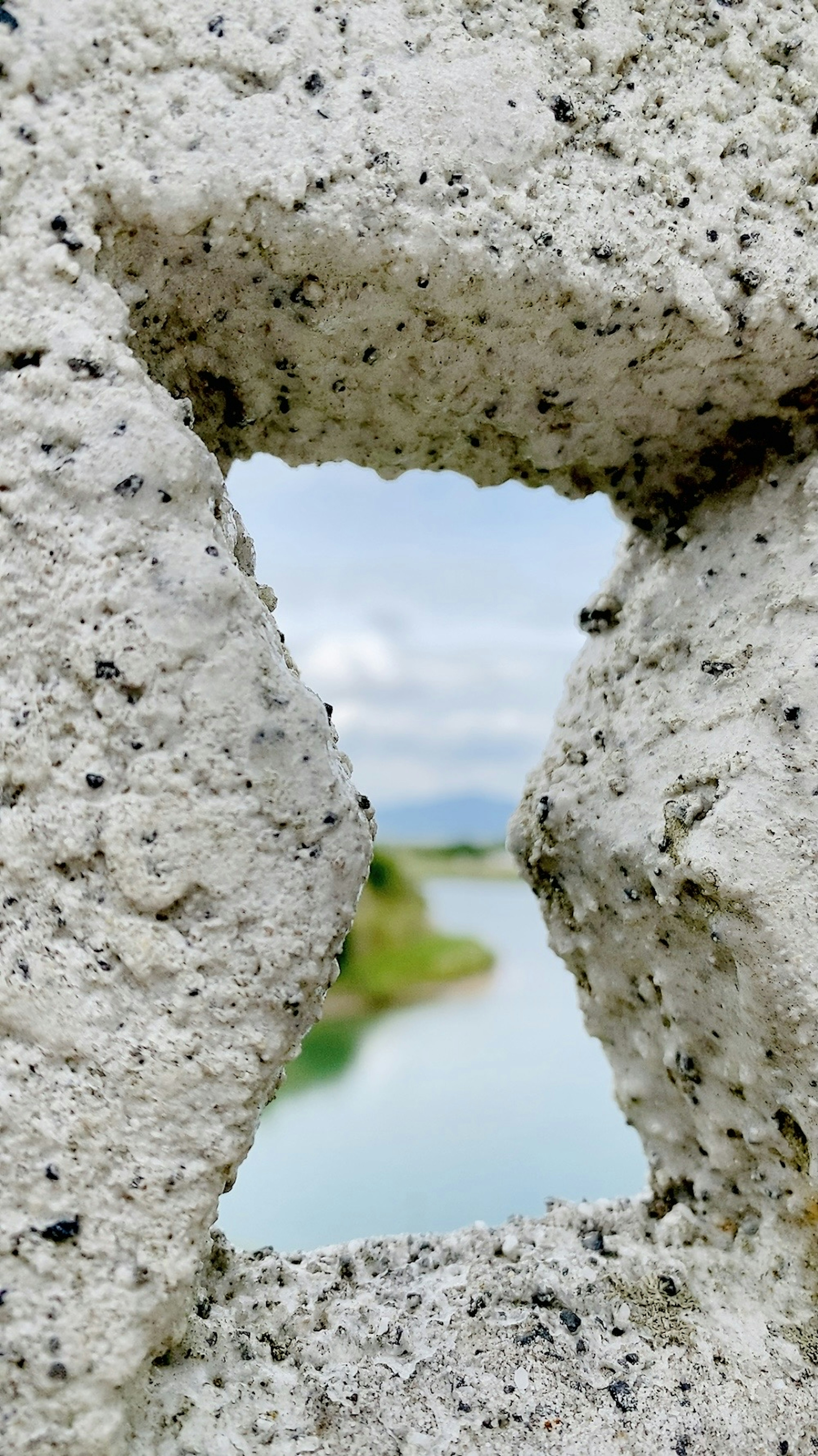 Vista di un fiume attraverso un buco in un muro di pietra