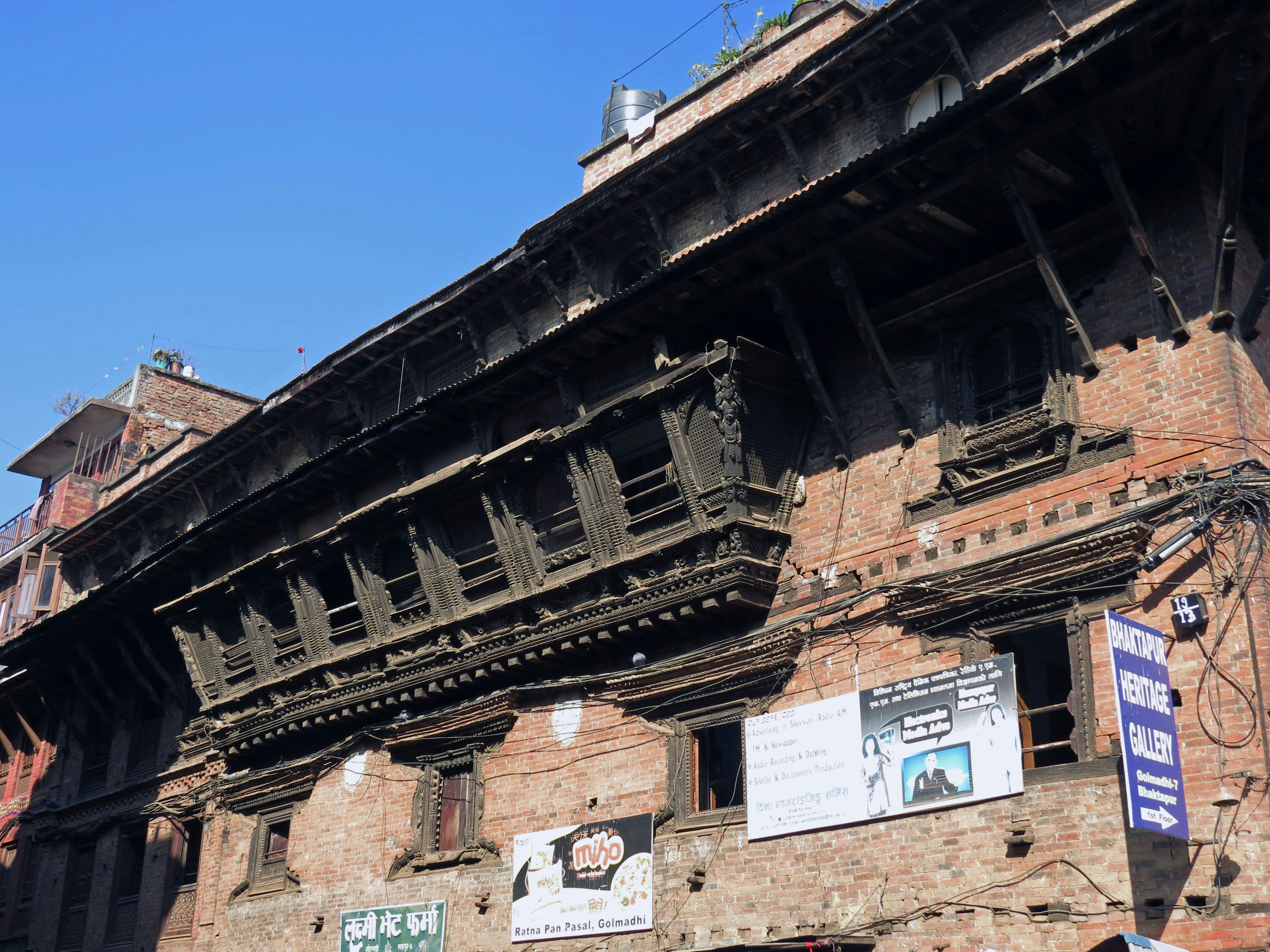 Fassade eines alten Backsteingebäudes mit einem vorspringenden Balkon und Schildern