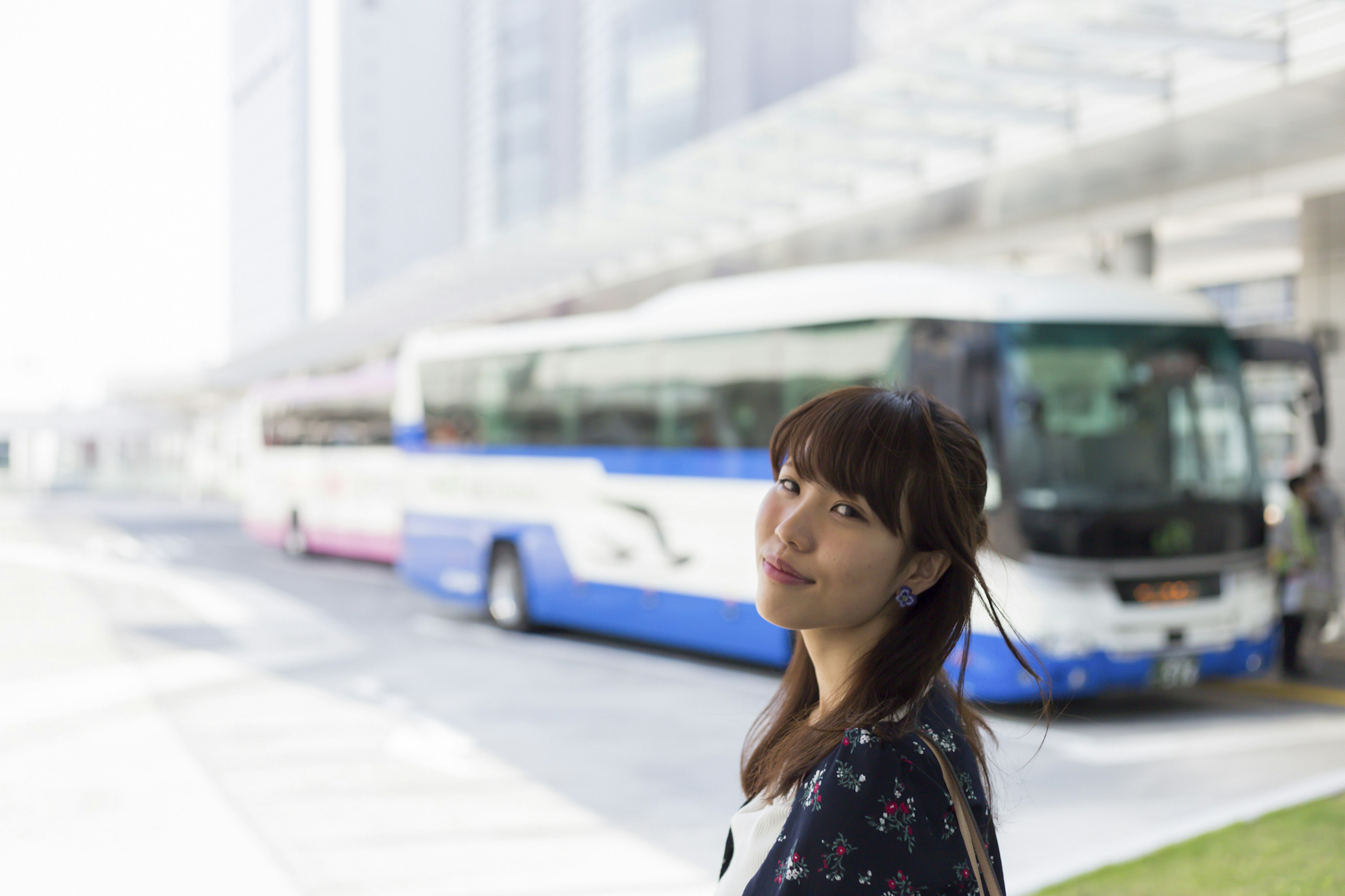 一名女性在公車站微笑，背景中有排列的公車