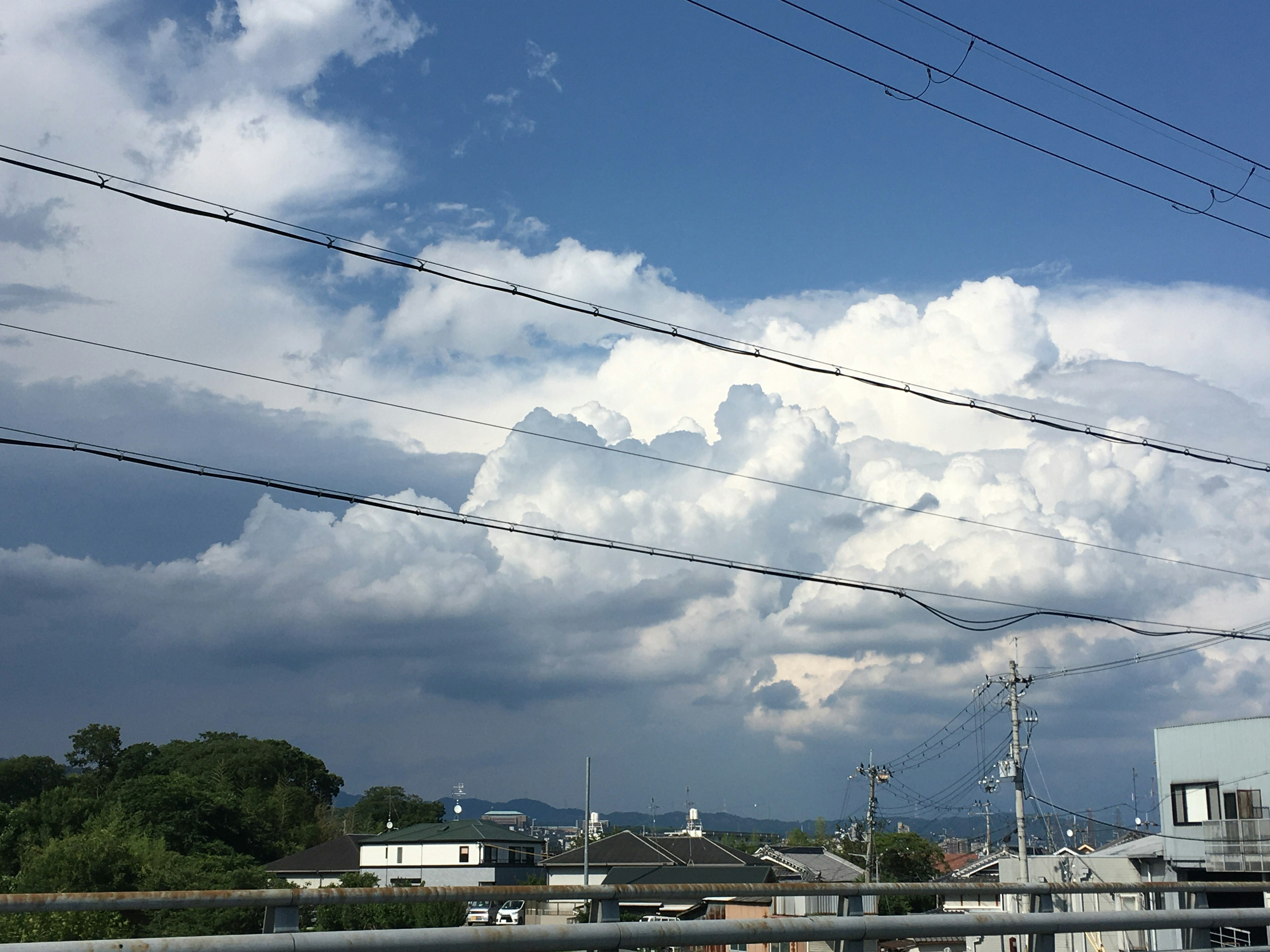 A landscape with blue sky and white clouds featuring visible power lines