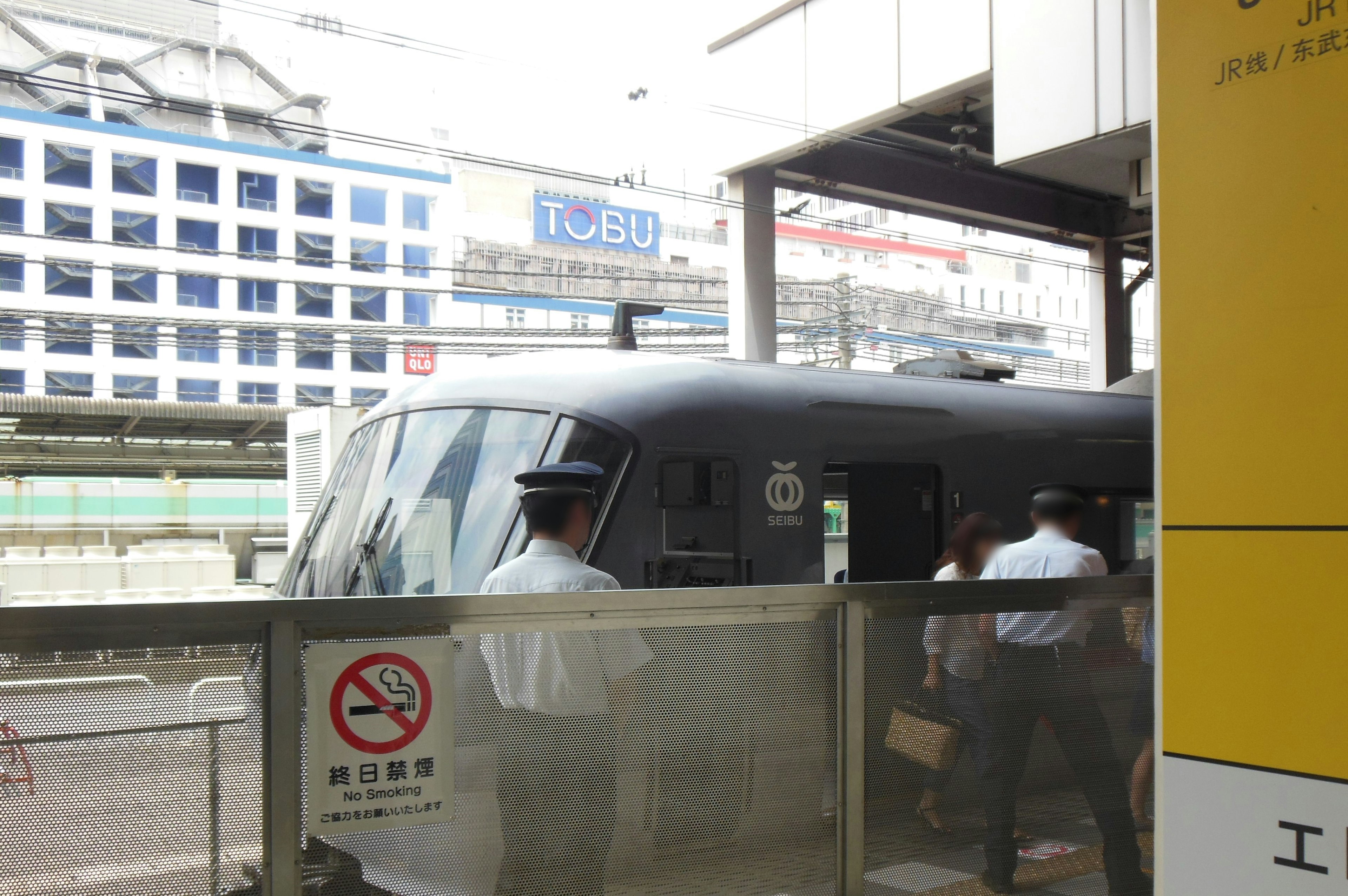 黒い電車が駅に停車している様子と乗客が乗り込む風景