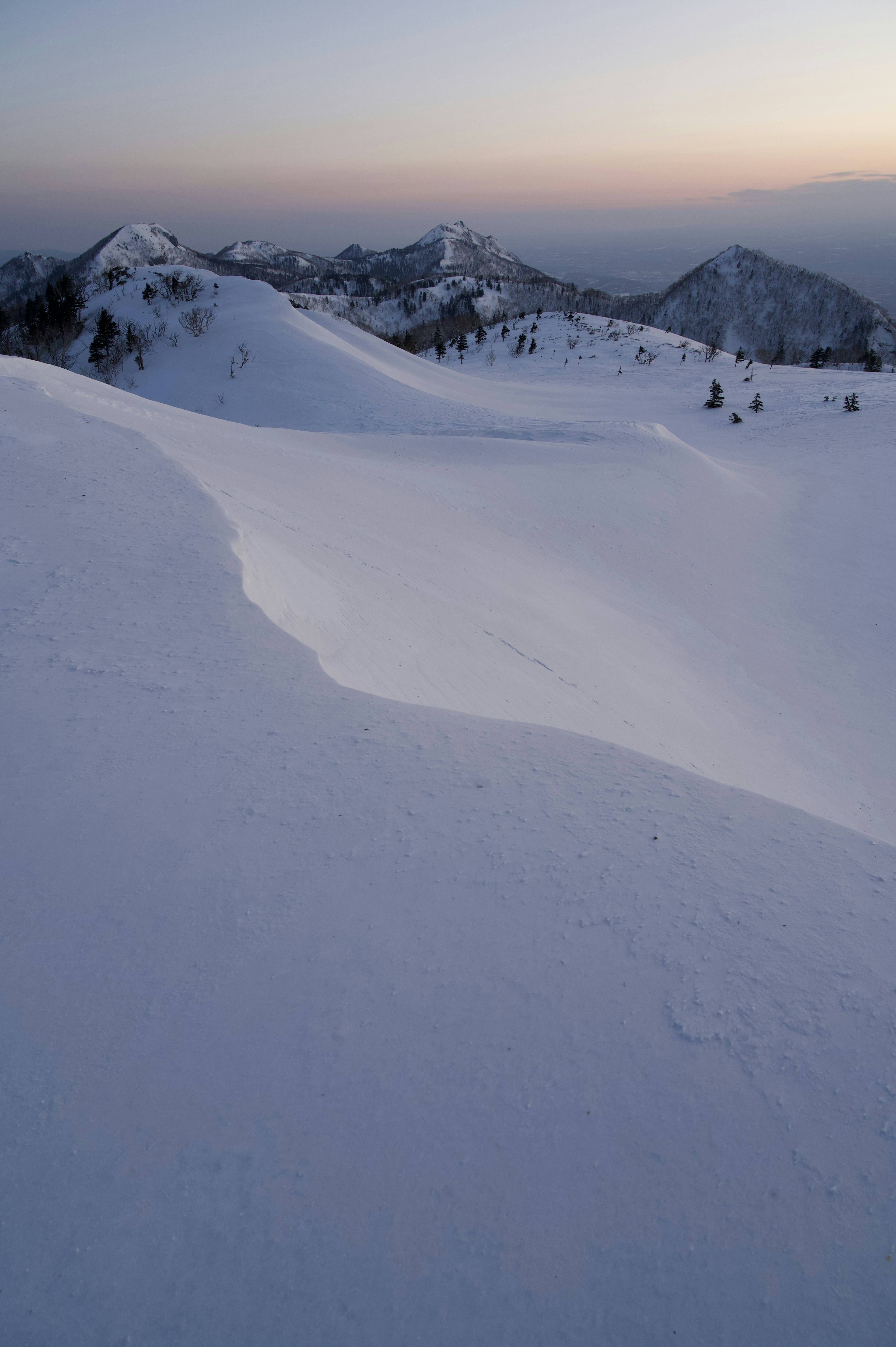 Snow-covered mountain landscape with soft sunset hues