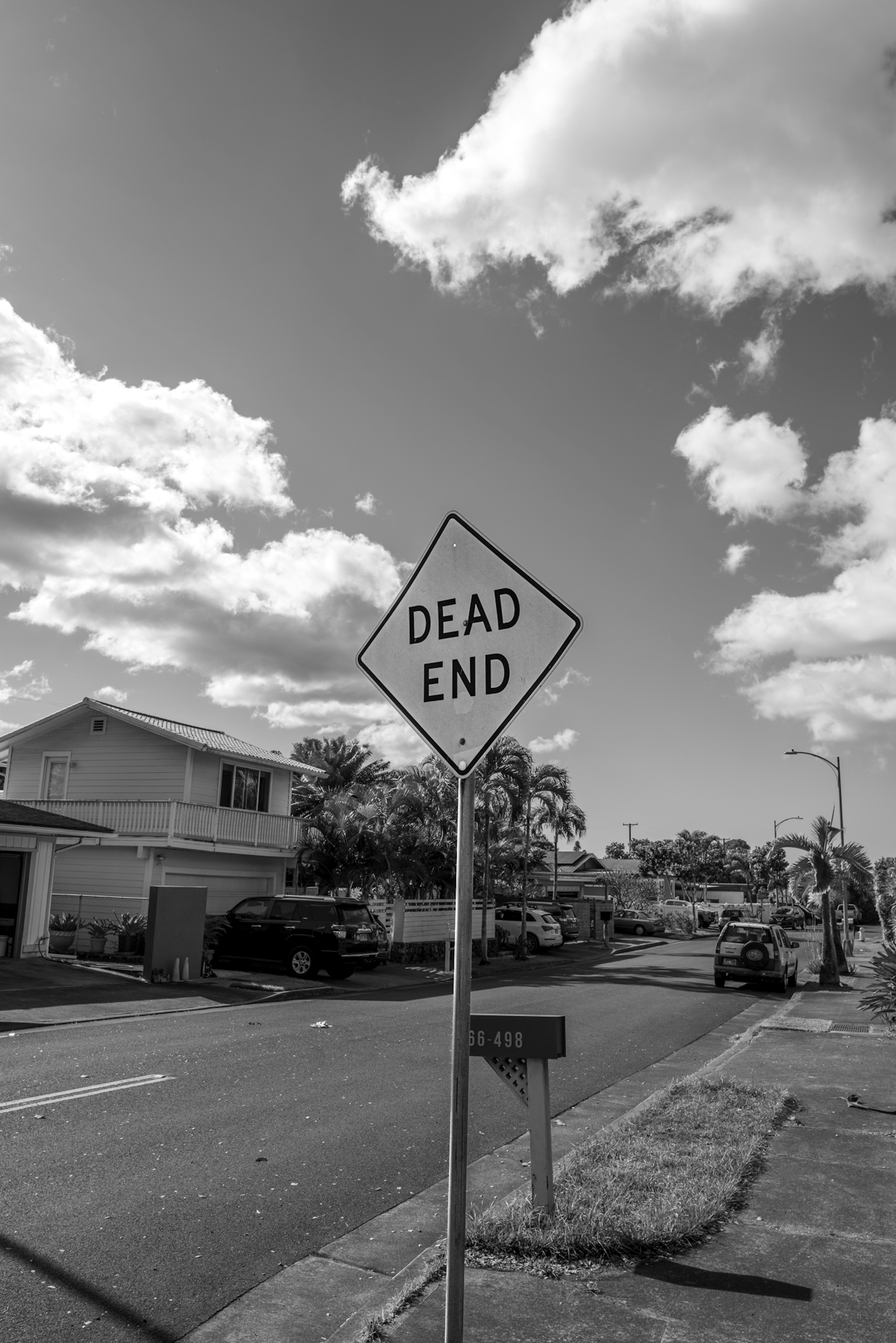 A dead end sign in a residential area with clouds