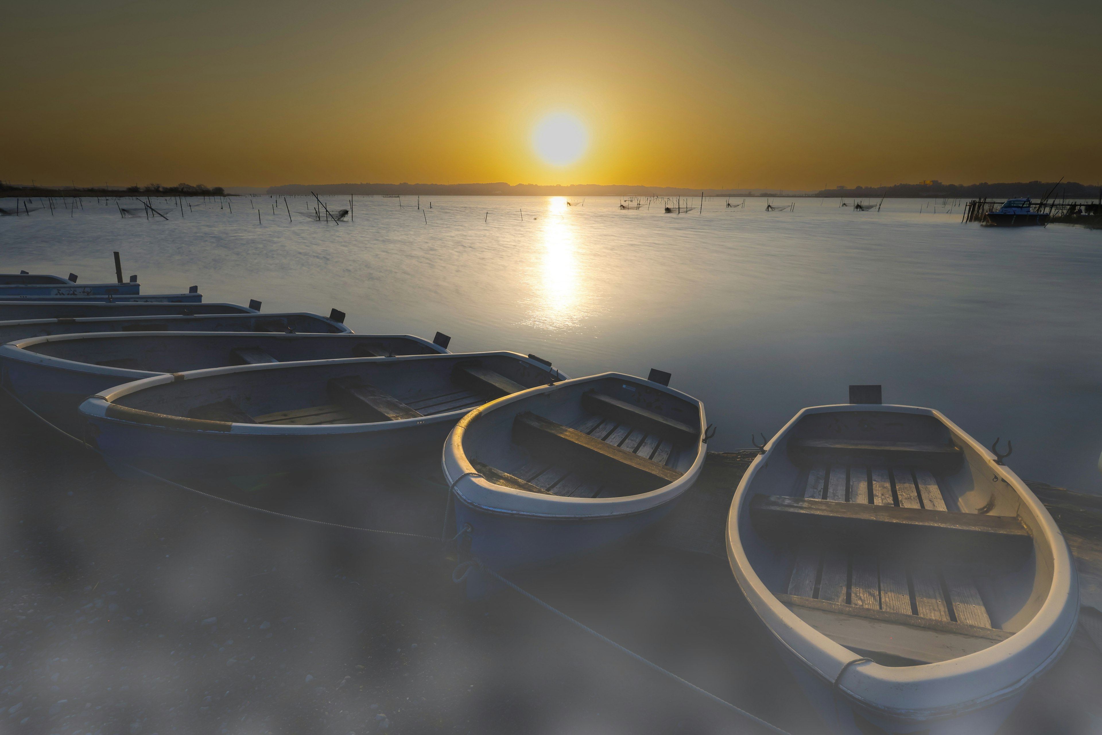 Serene landscape of boats on calm water with a sunset