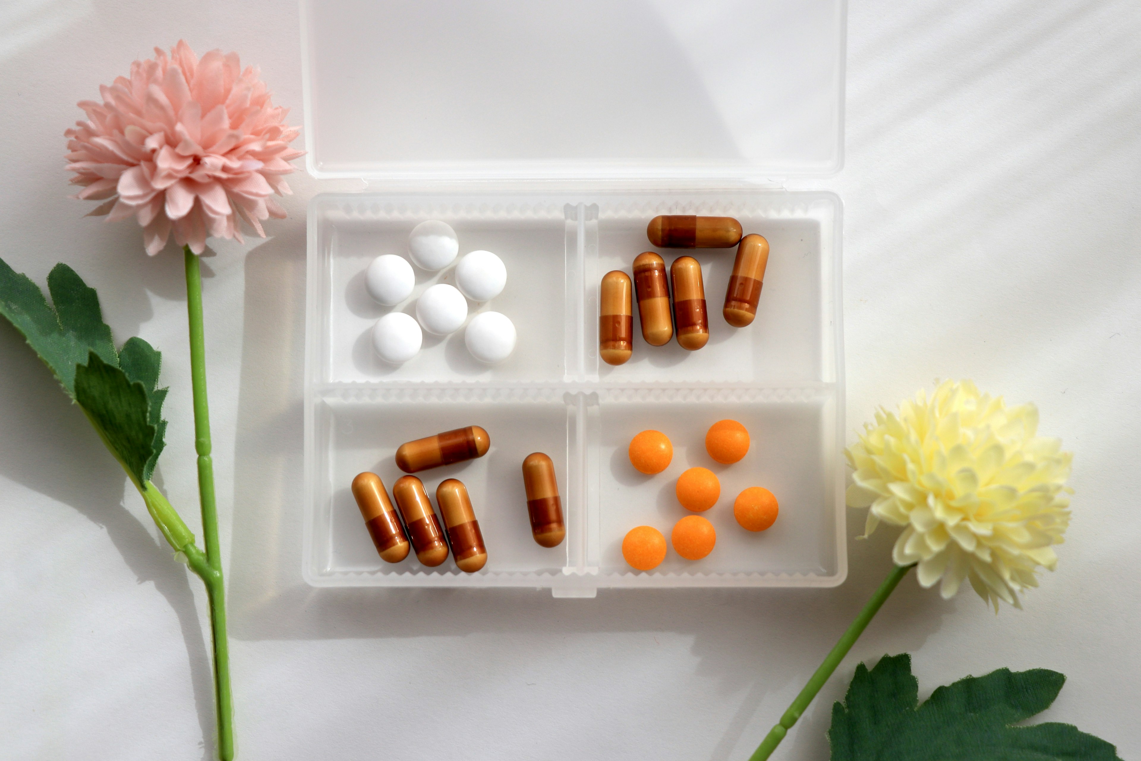 A transparent case filled with various colored pills and flowers