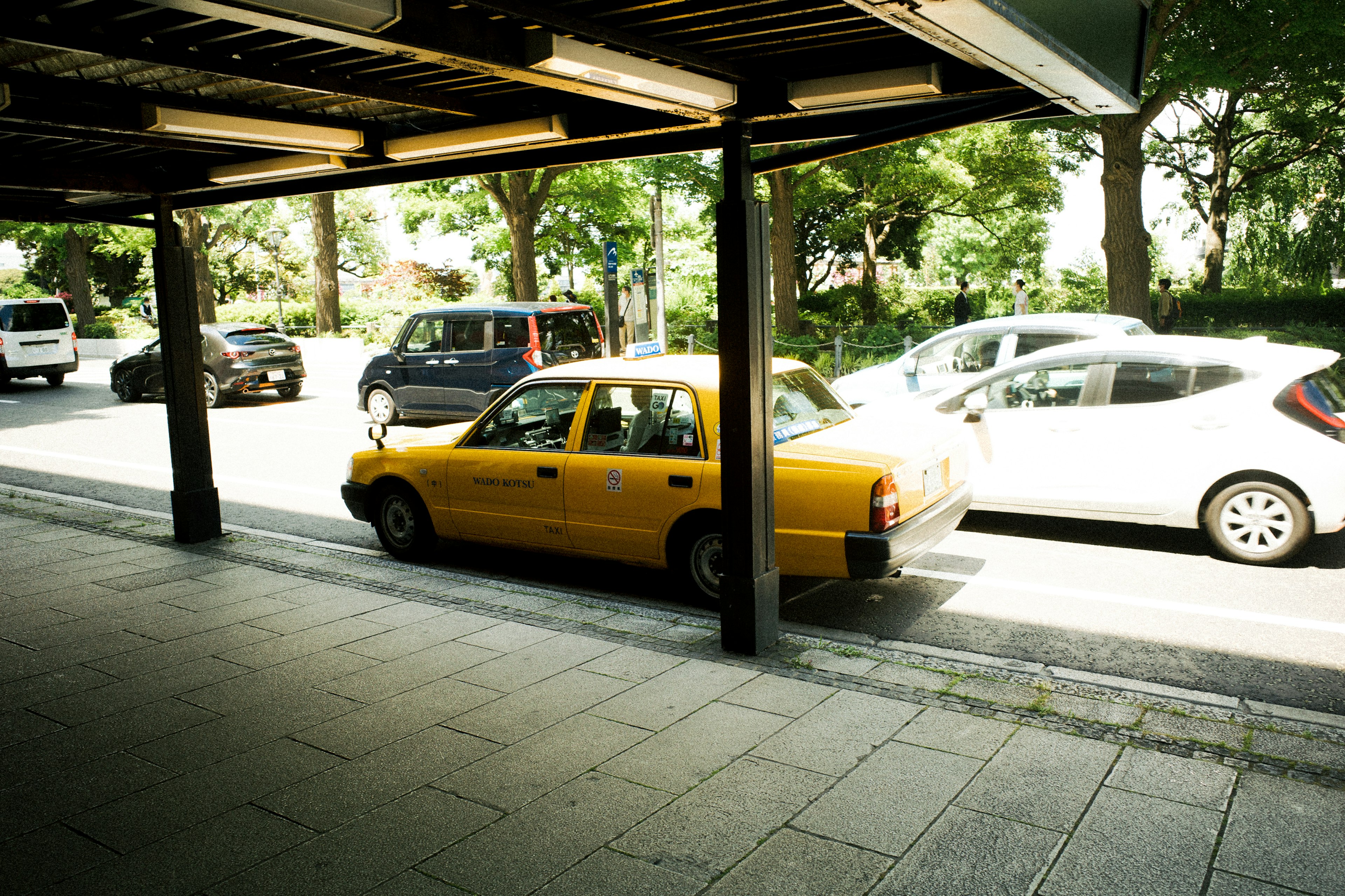 舗装された道路に駐車した黄色いタクシーと他の車両の風景