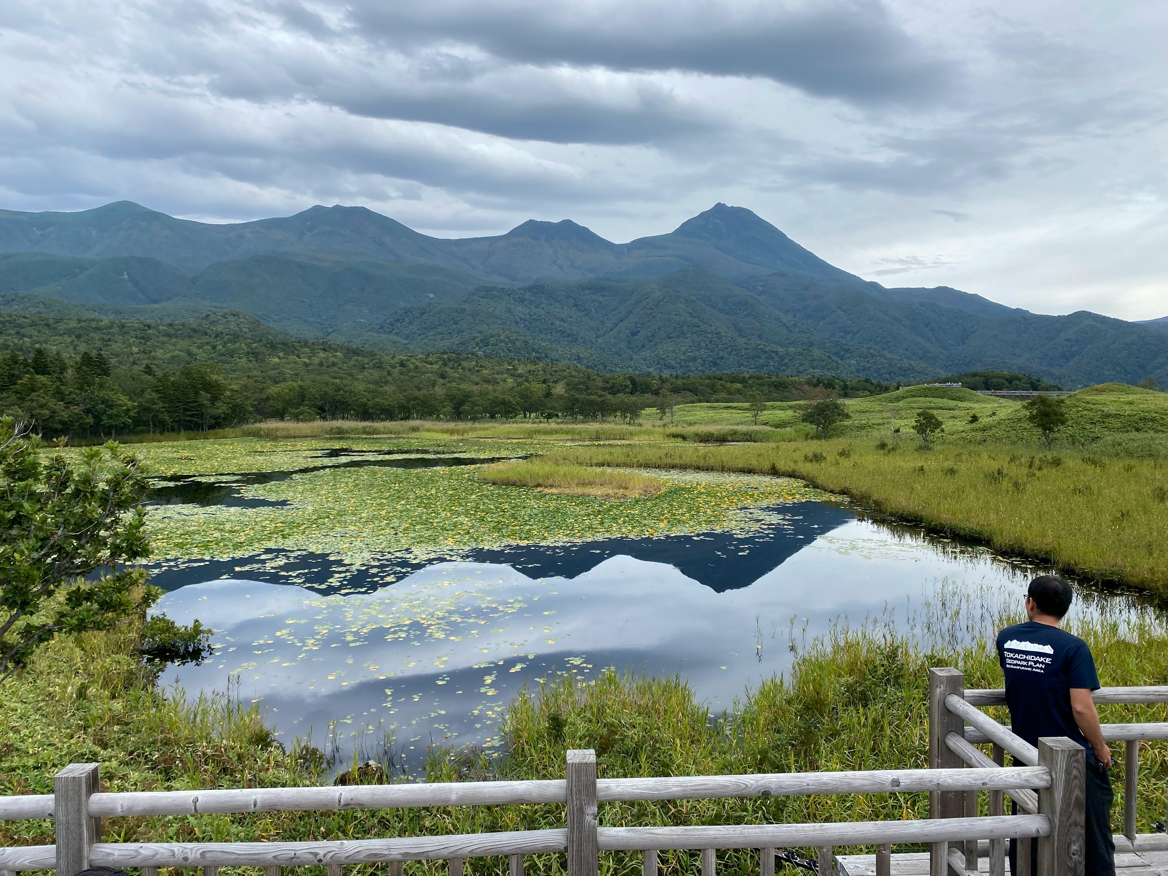 山々と静かな池の風景を眺める人