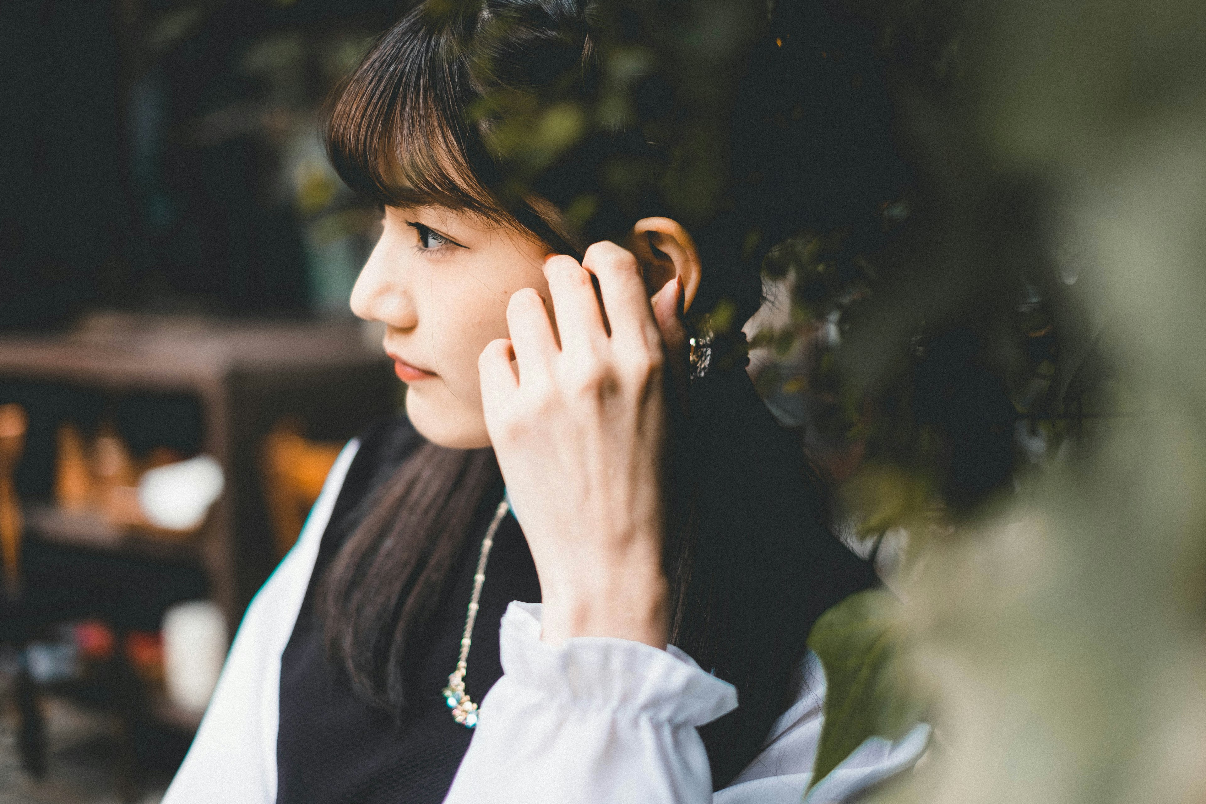 Profile of a woman wearing earbuds with a green background and soft lighting