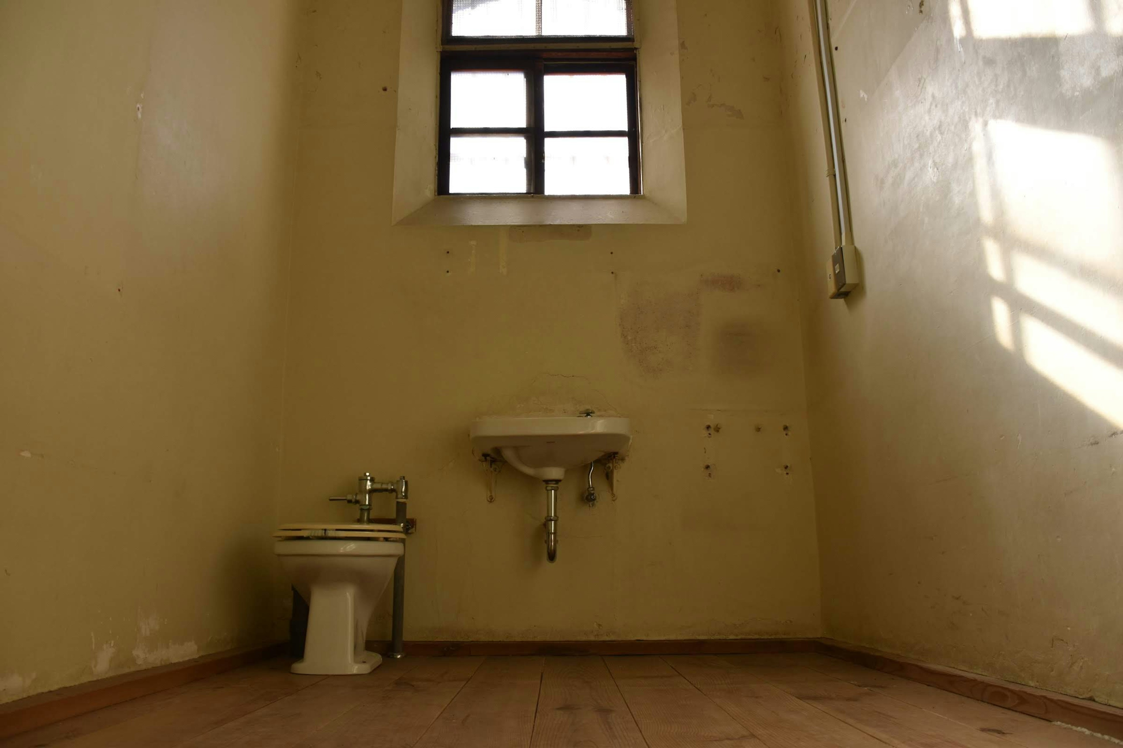 Intérieur de salle de bain faiblement éclairé avec des murs vert-jaune et une fenêtre laissant entrer la lumière naturelle