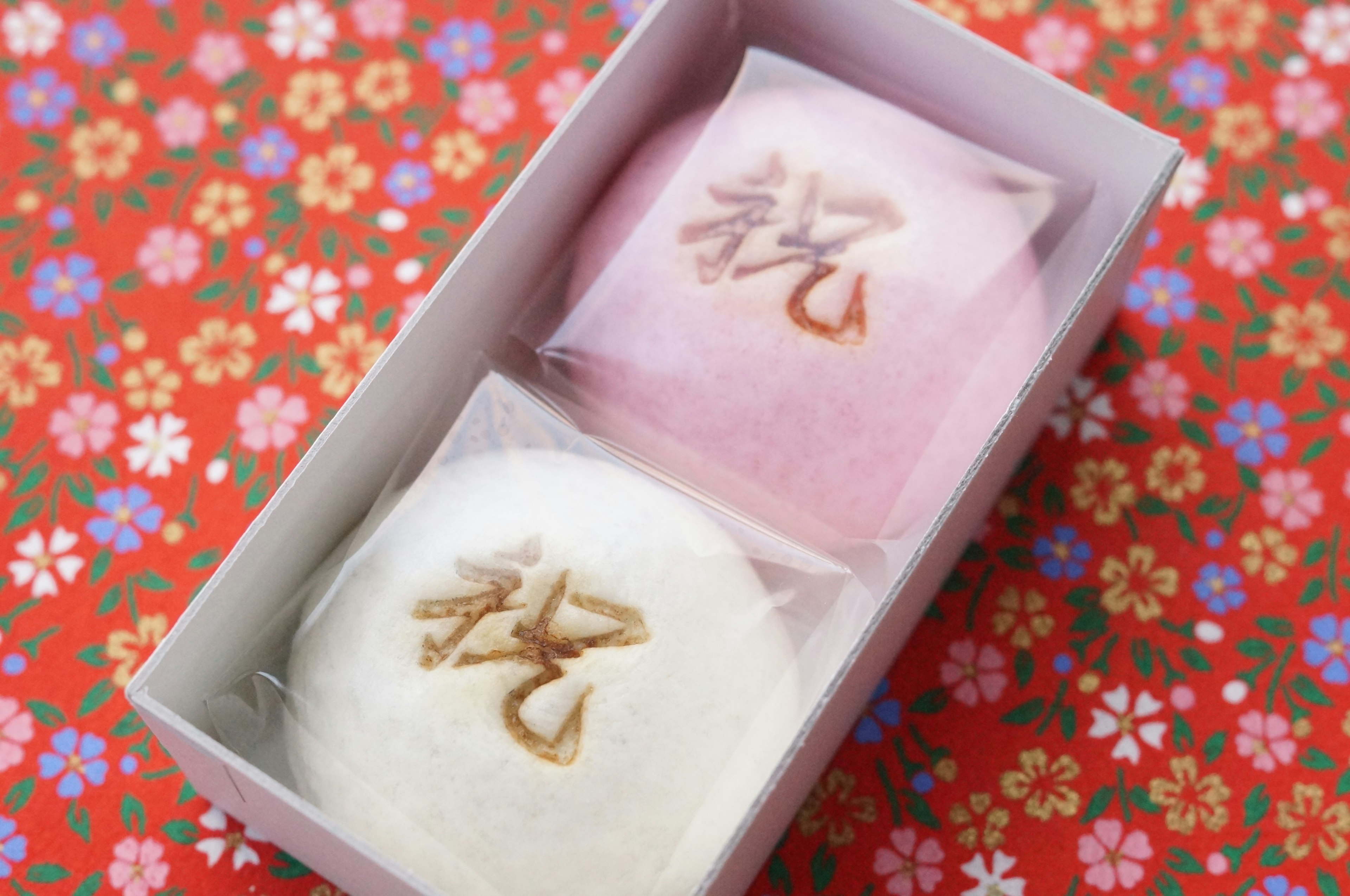 Une boîte contenant des douceurs japonaises rose et blanche avec un fond floral