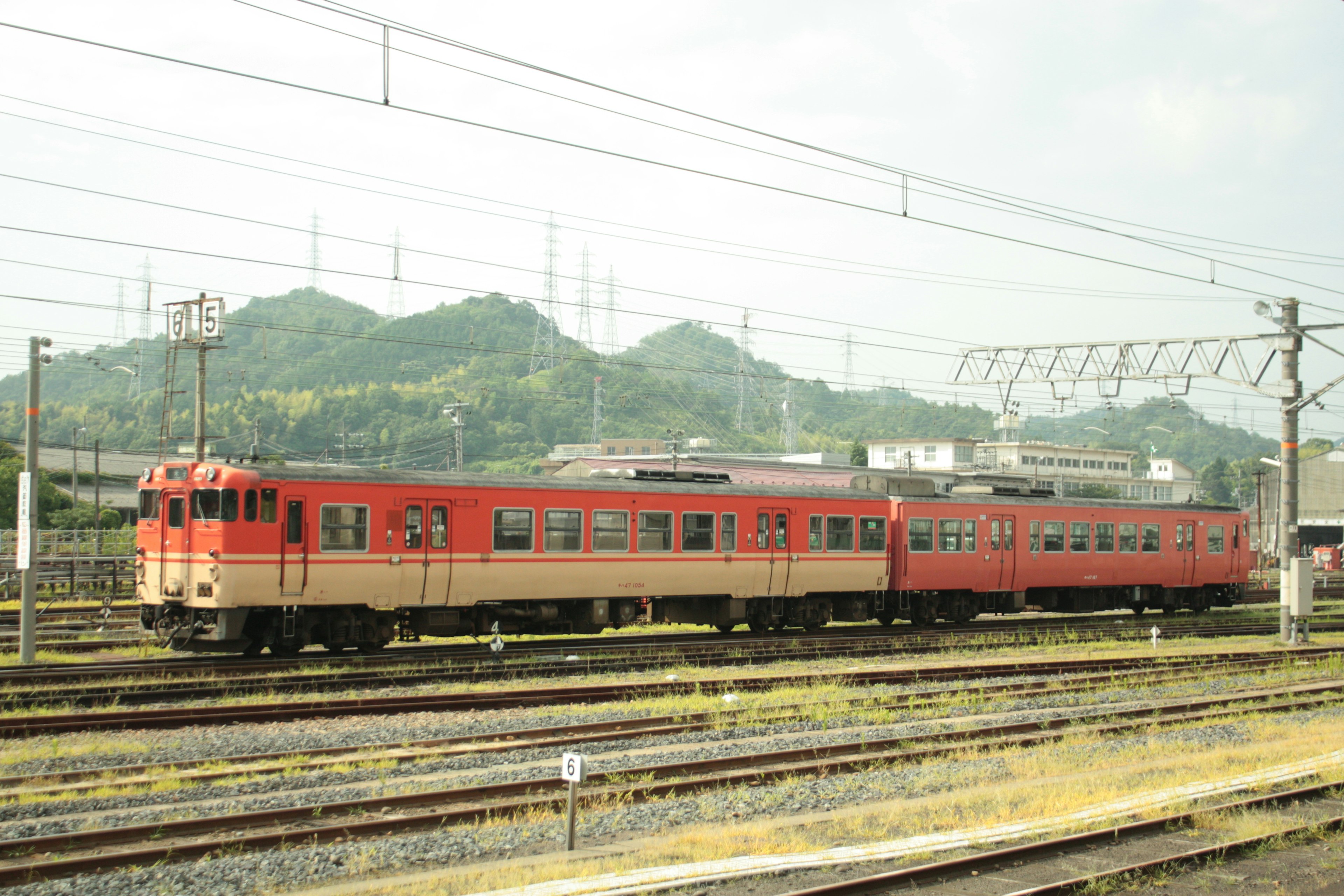 赤とクリーム色の列車が鉄道の線路に停車している風景