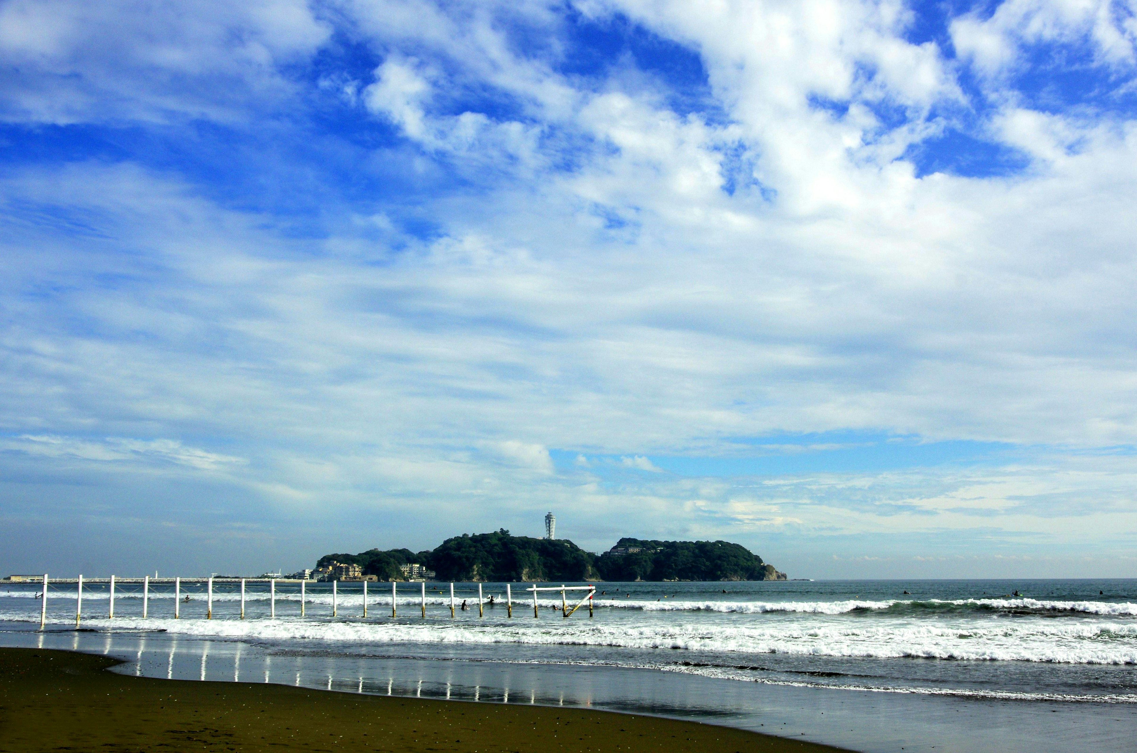 Pemandangan pantai dengan langit biru dan awan putih di atas ombak lautan