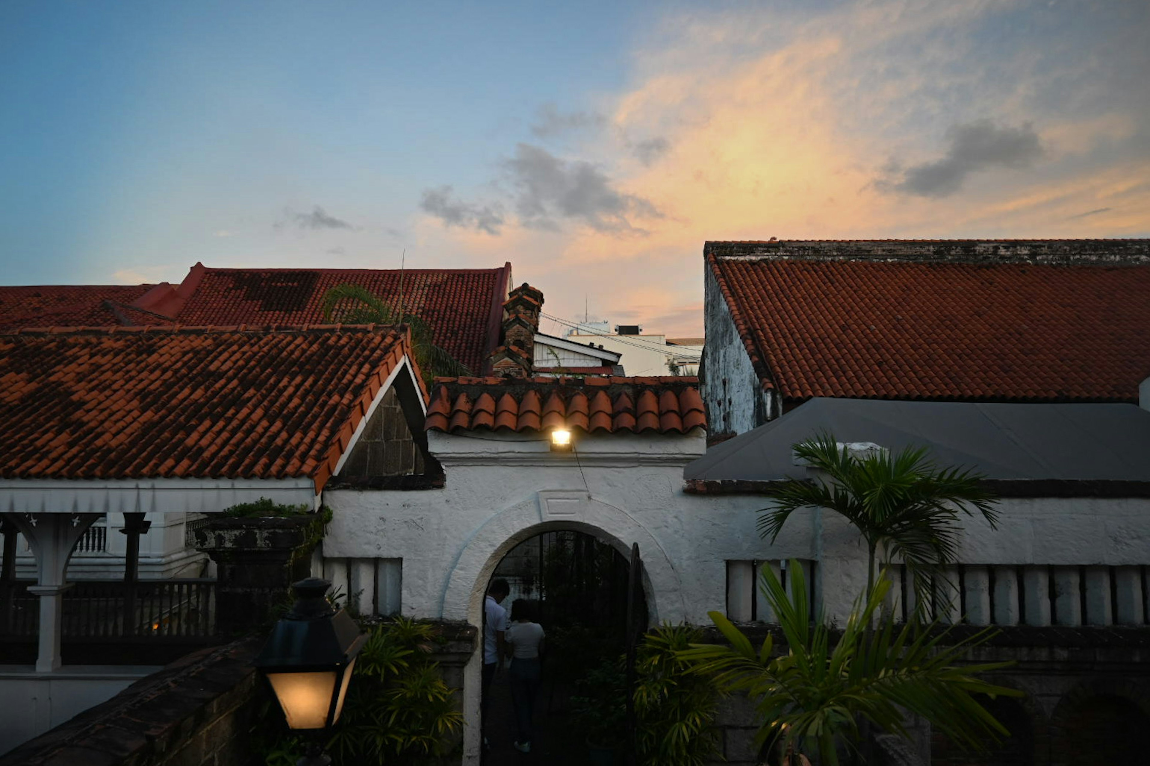 White archway with red roofs against a sunset sky