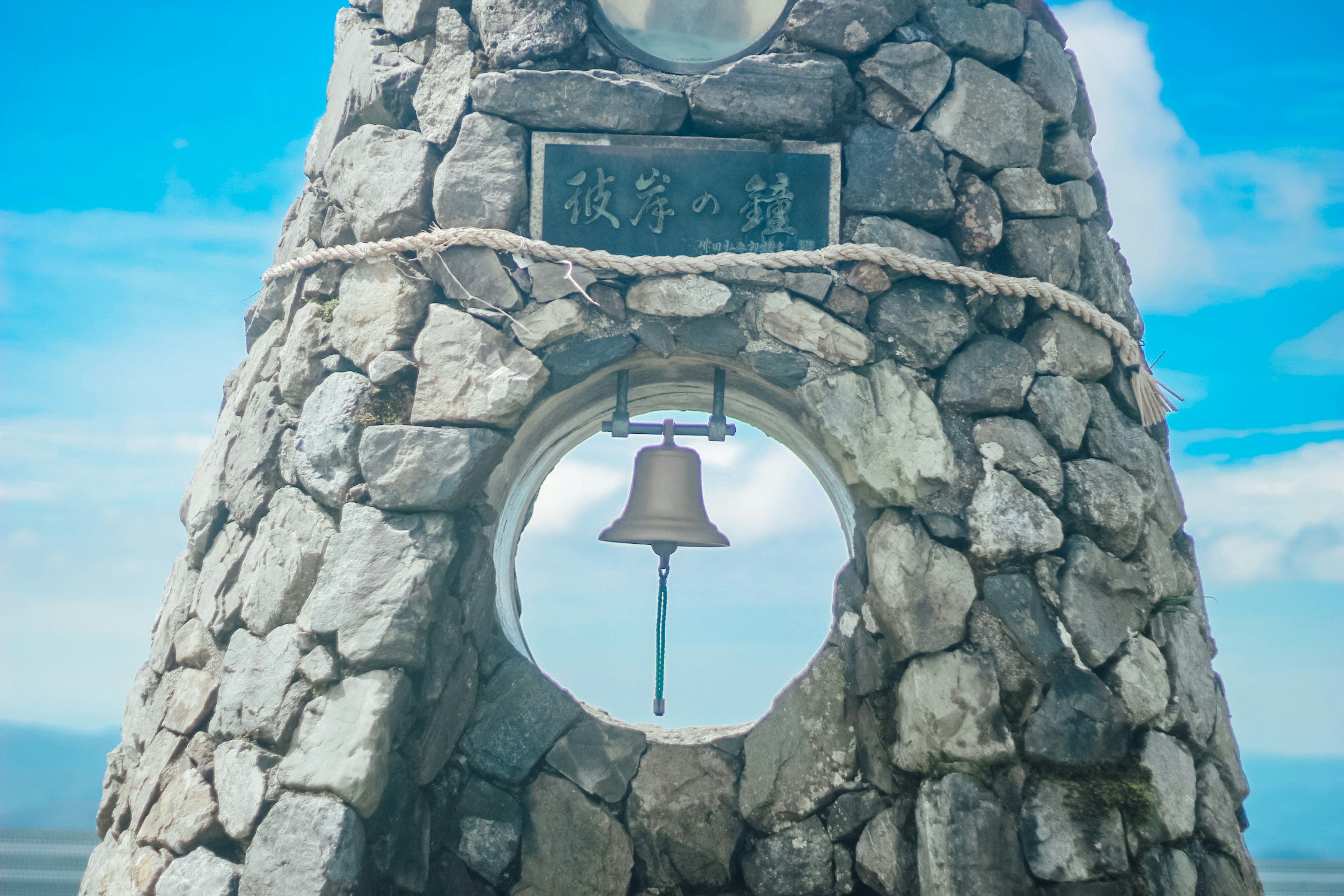 Stone tower with a bell and a scenic background