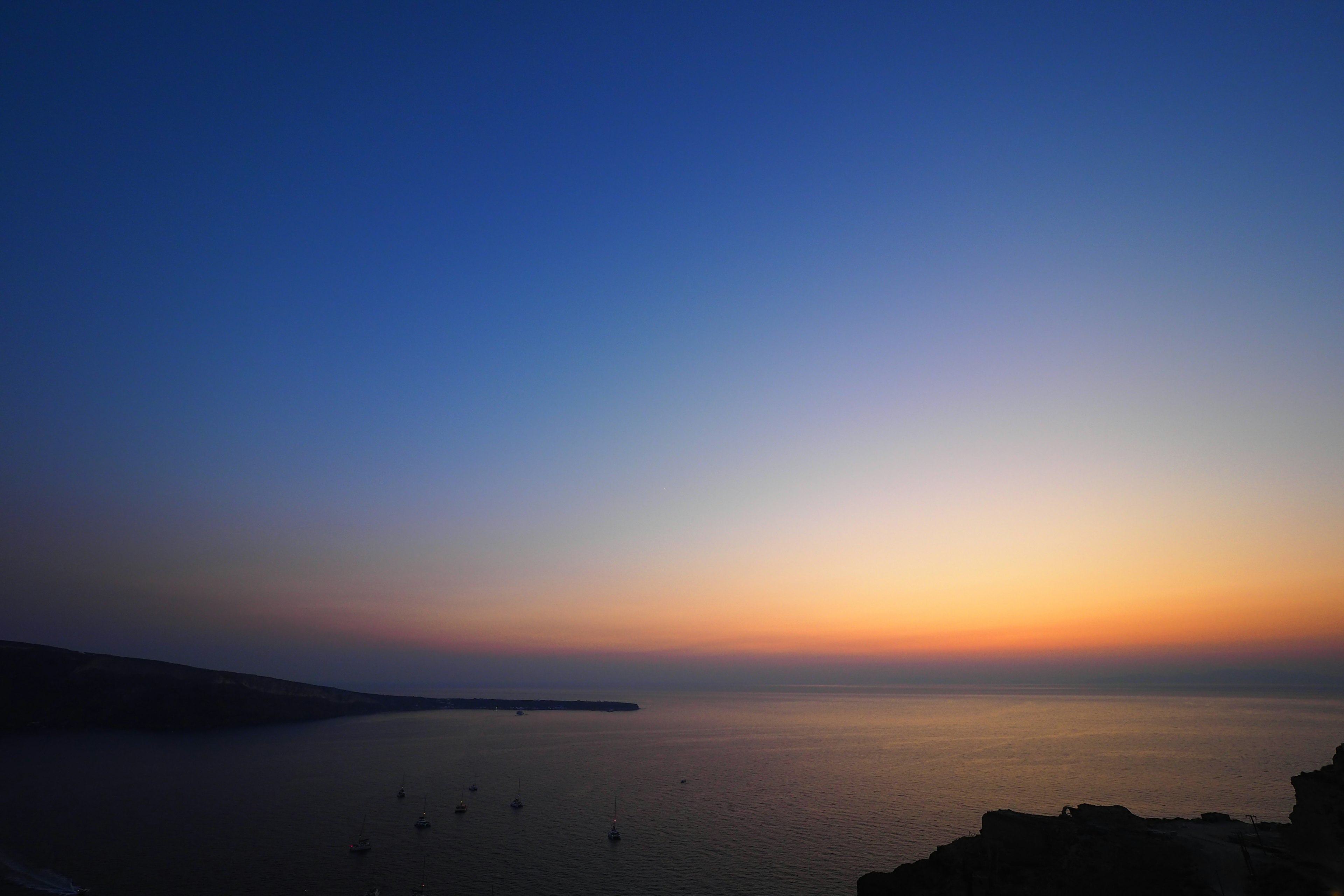 青い空とオレンジの夕日が映る海の風景