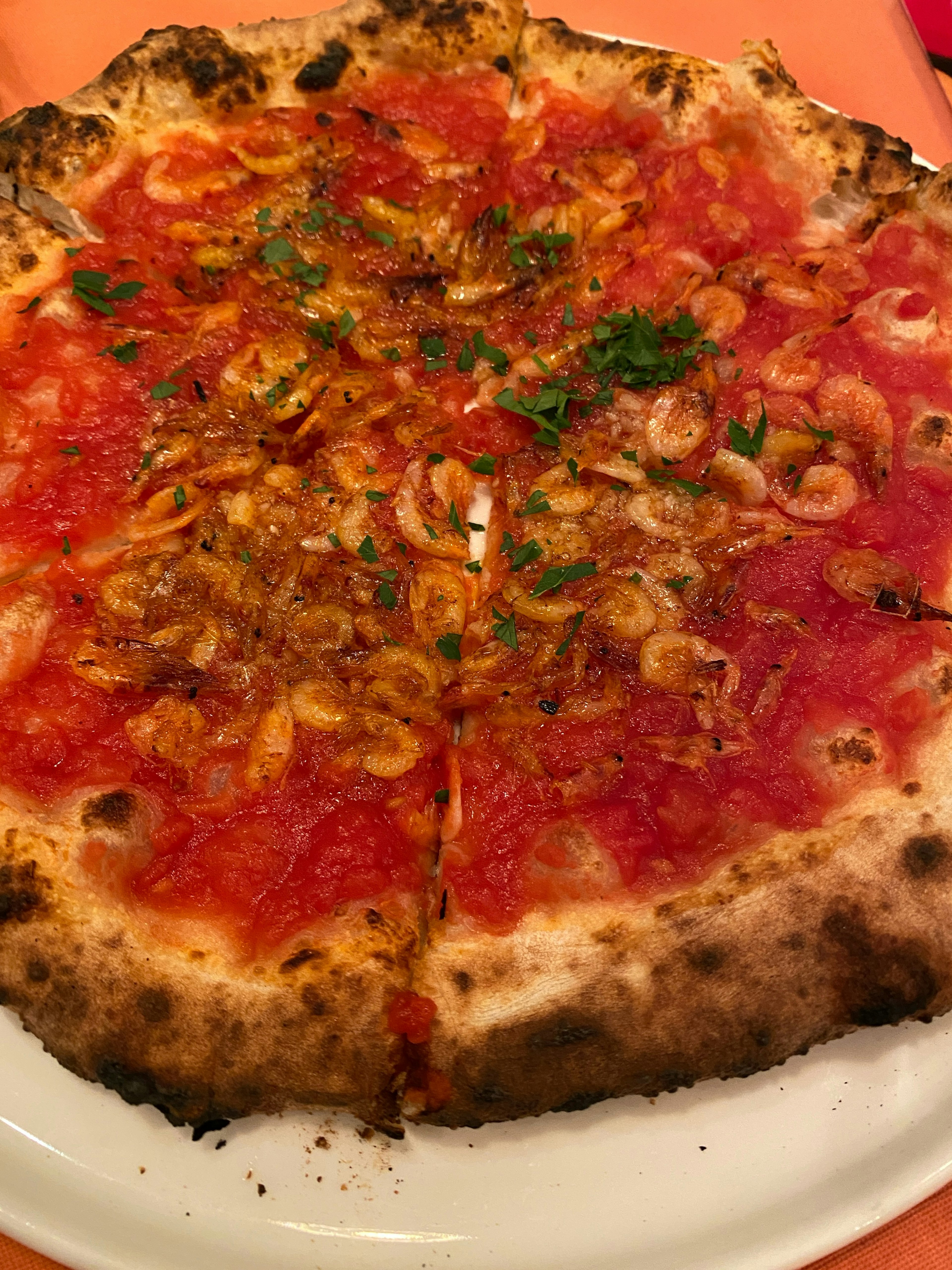 Metà di una pizza con salsa di pomodoro e gamberetti su una crosta rustica