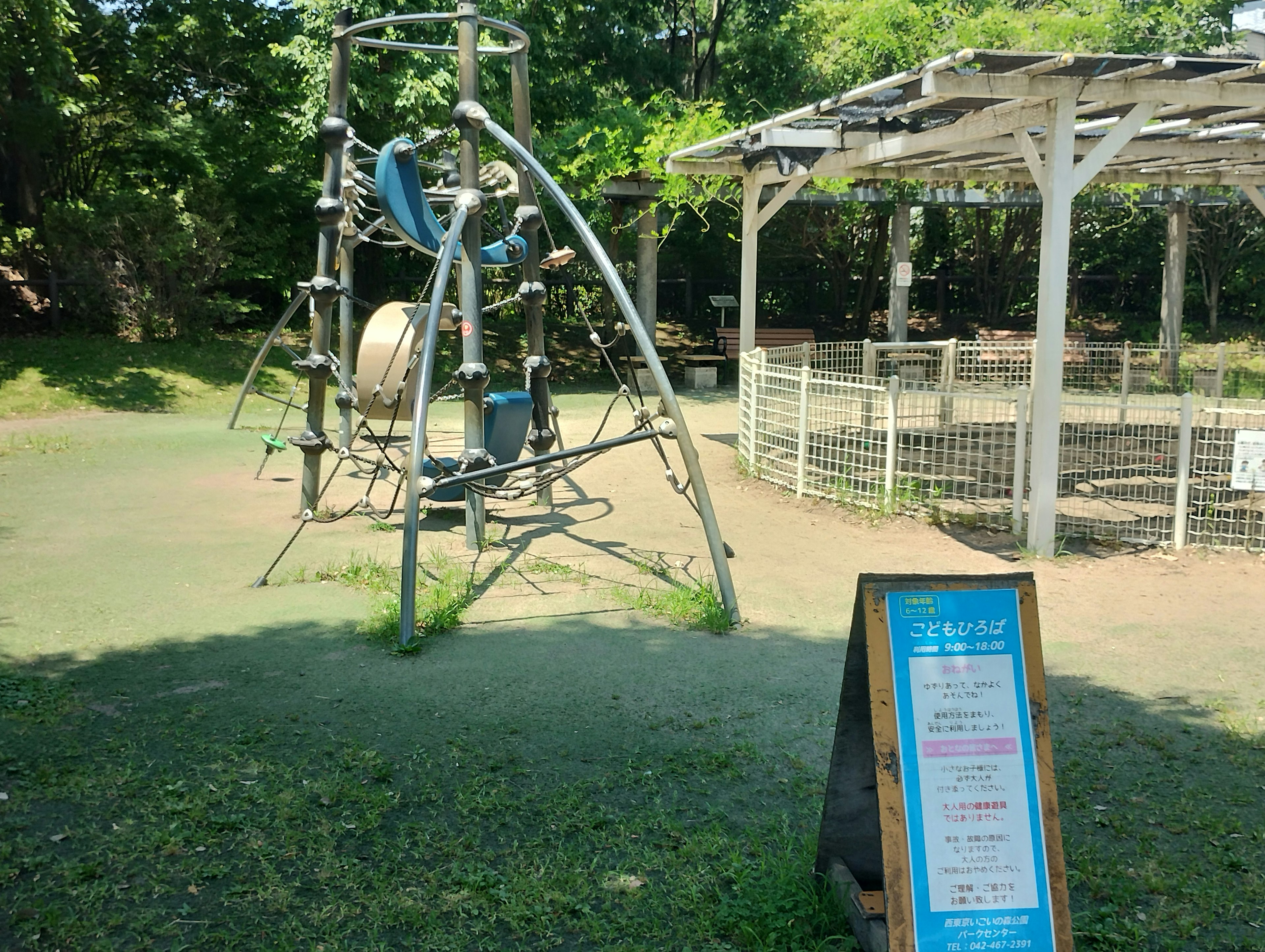 잔디가 깔린 공원 지역에 있는 놀이터 장비와 표지판