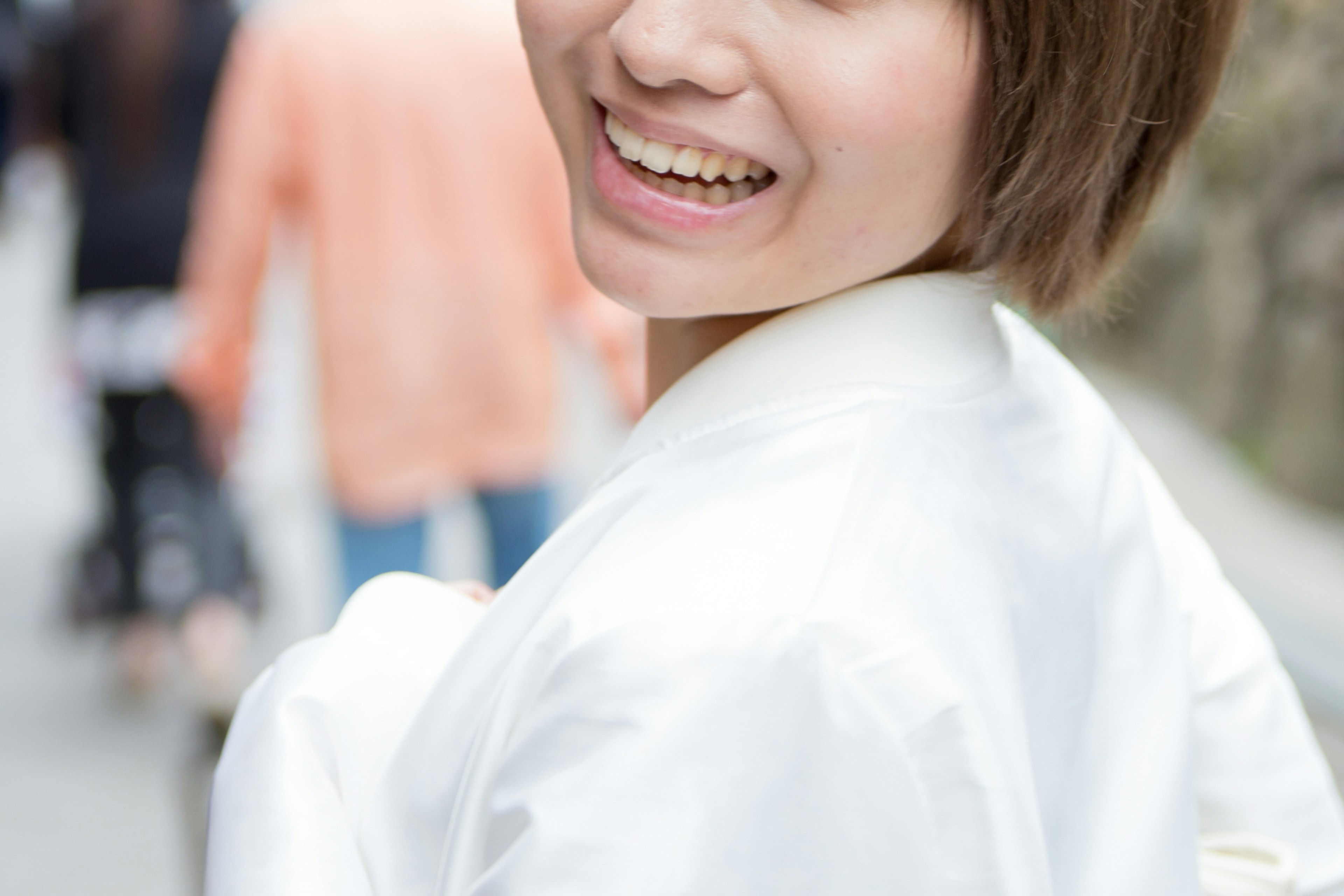 Mujer sonriente con atuendo blanco y personas caminando al fondo