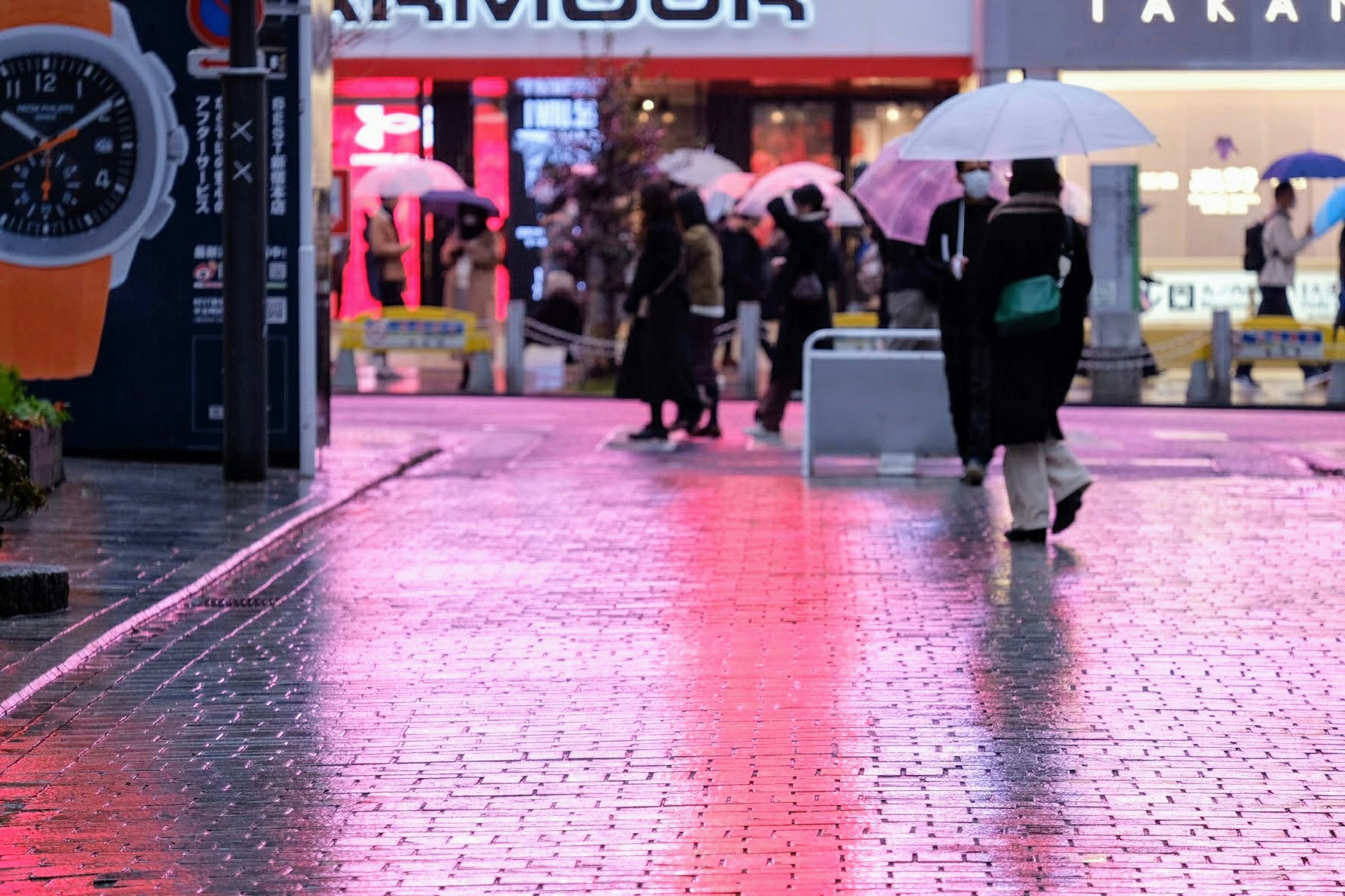 Menschen, die bei Regen mit Regenschirmen auf einem reflektierenden Gehweg gehen