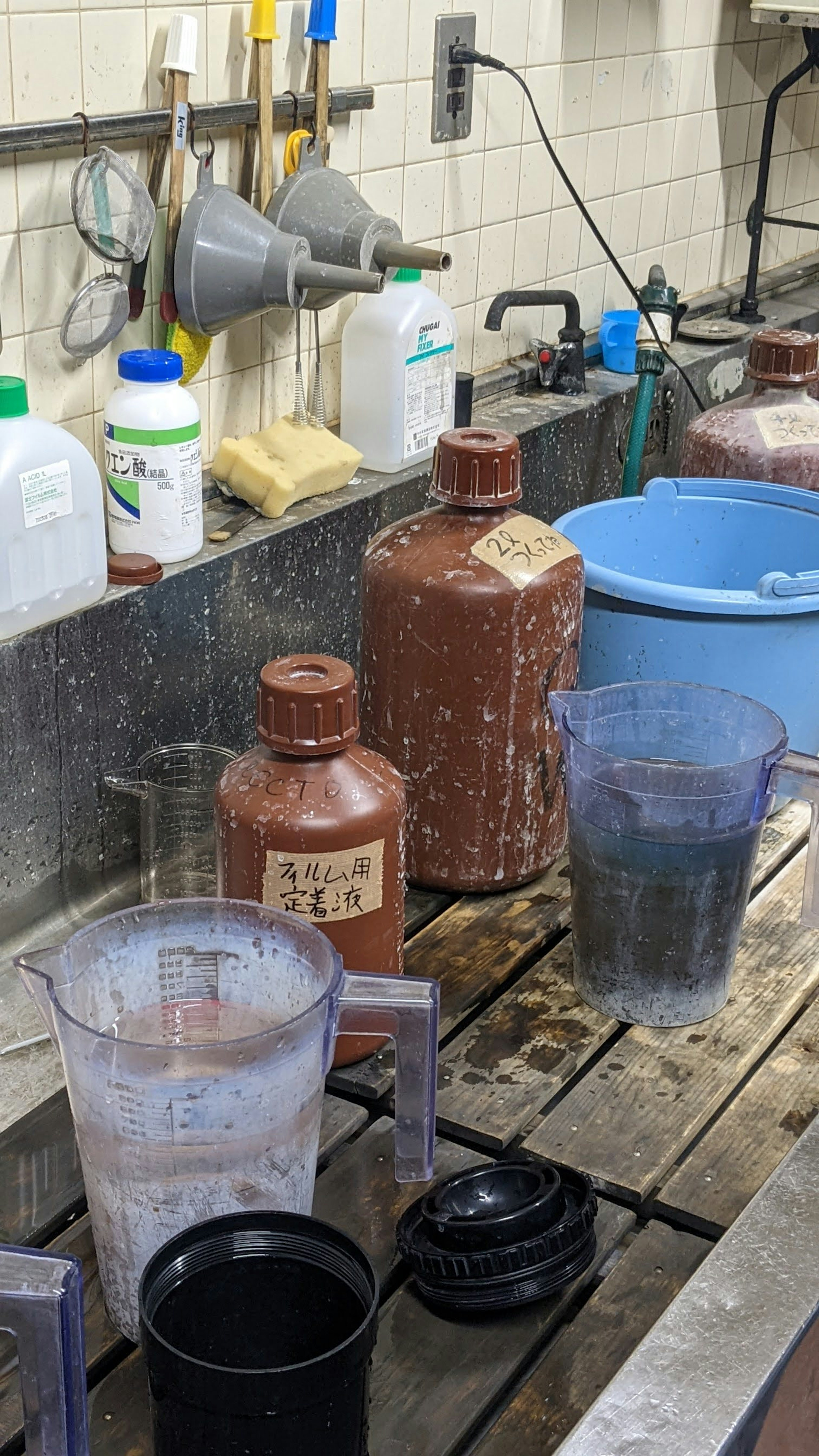 Lab sink with measuring cups and chemical bottles arranged