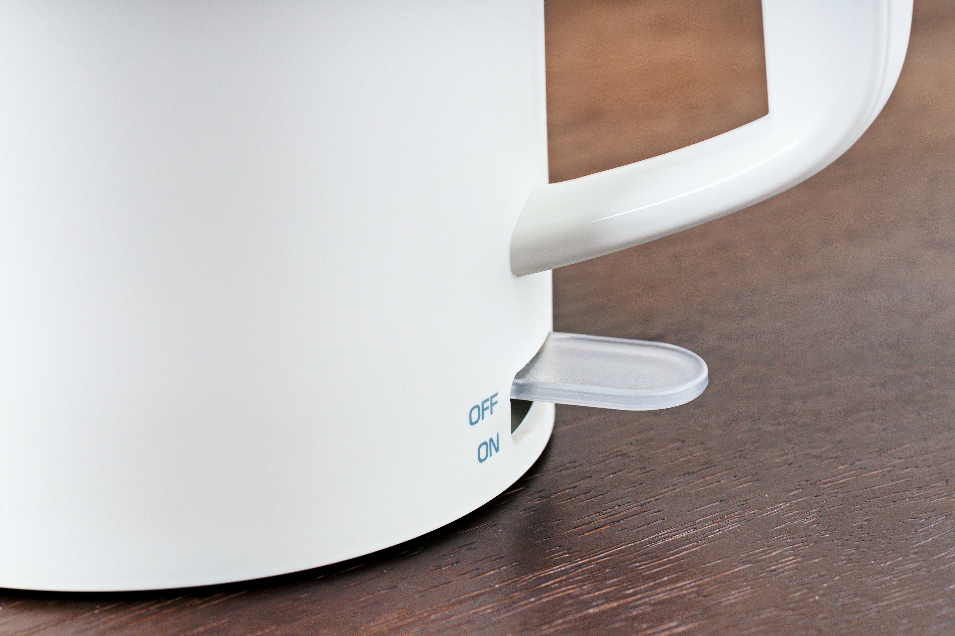 Close-up of a white electric kettle with an on-off switch