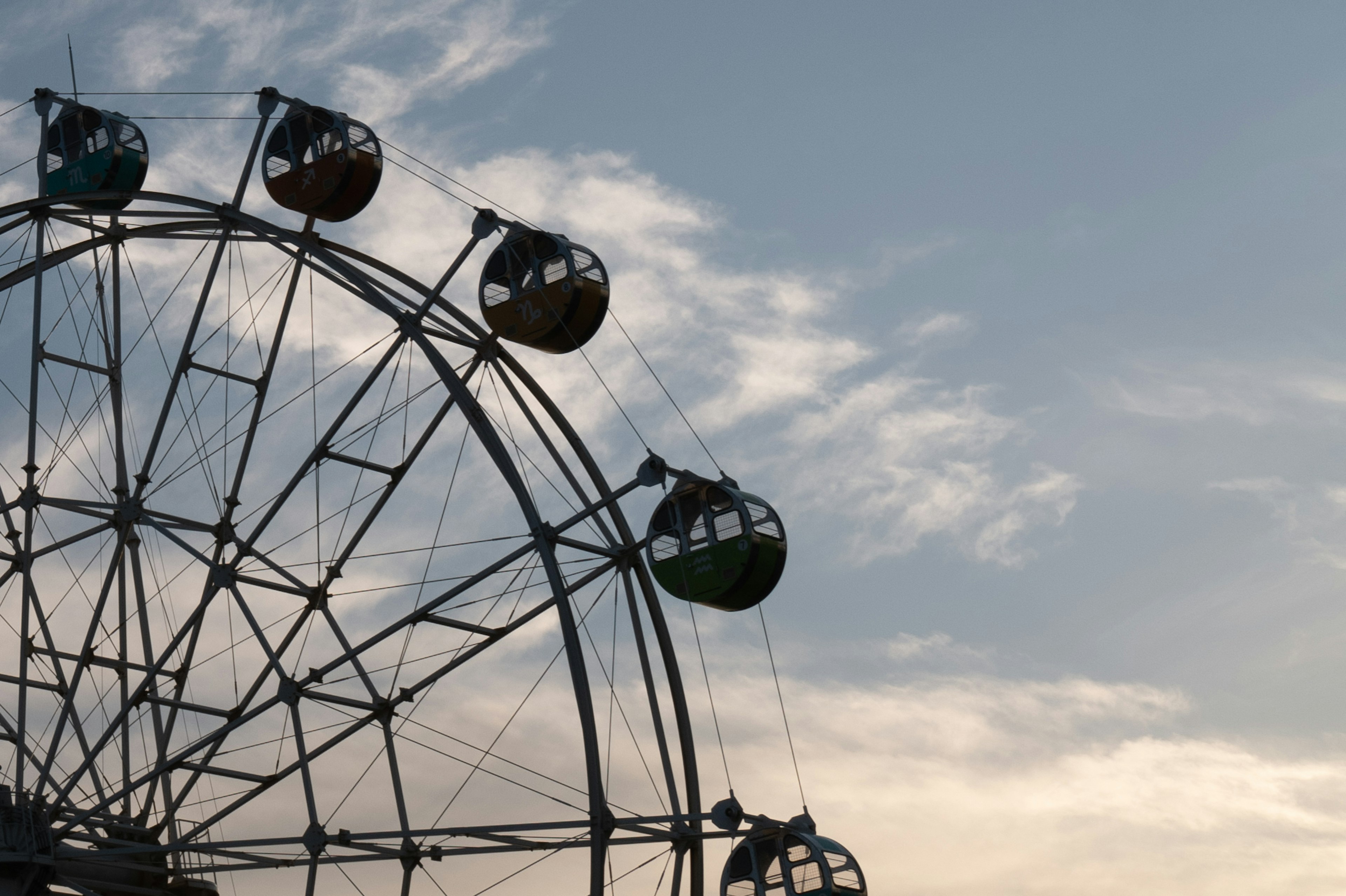 Silhouette of a Ferris wheel against a blue sky