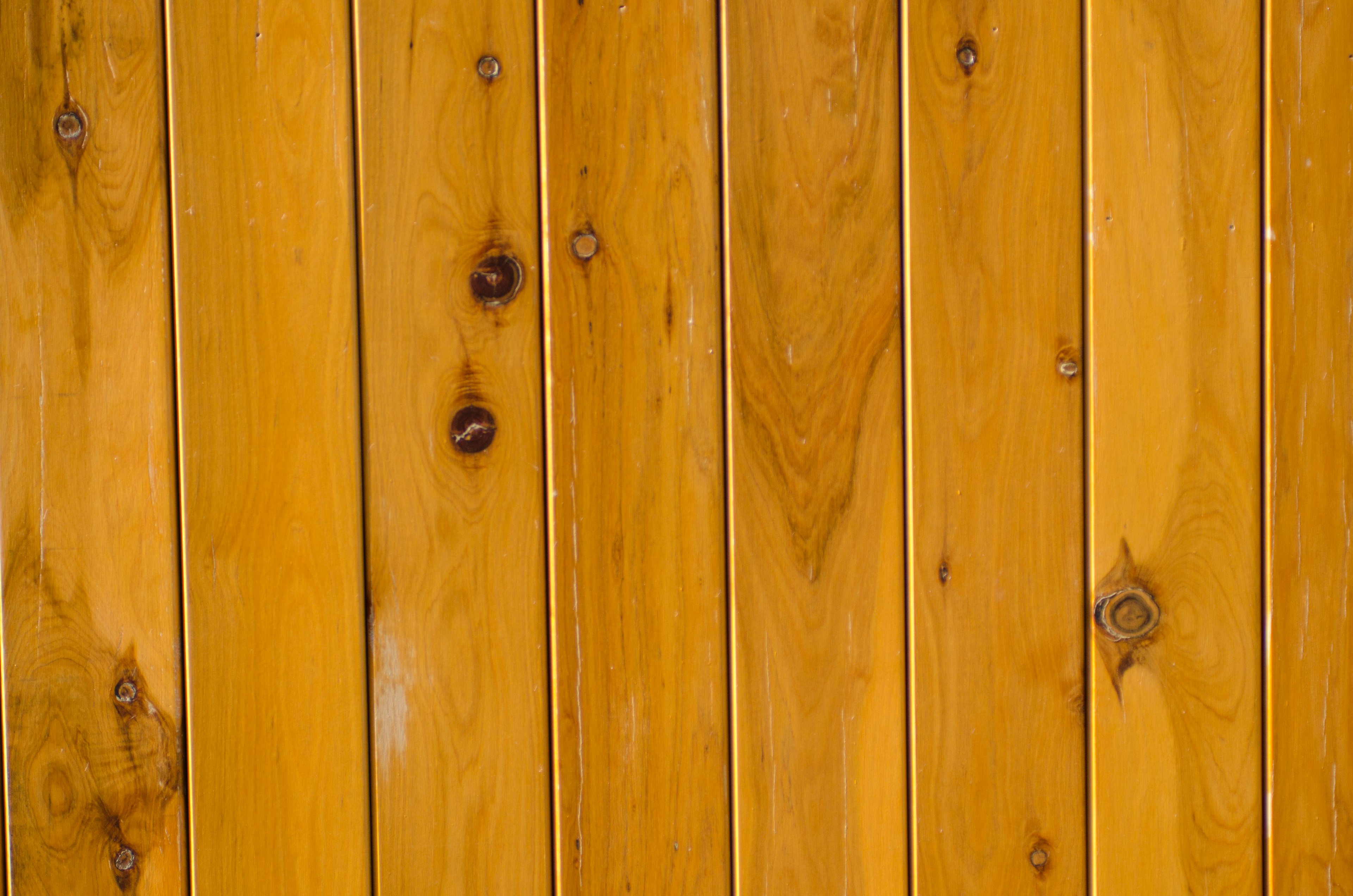 Textured wooden wall with warm yellow tones and visible knots