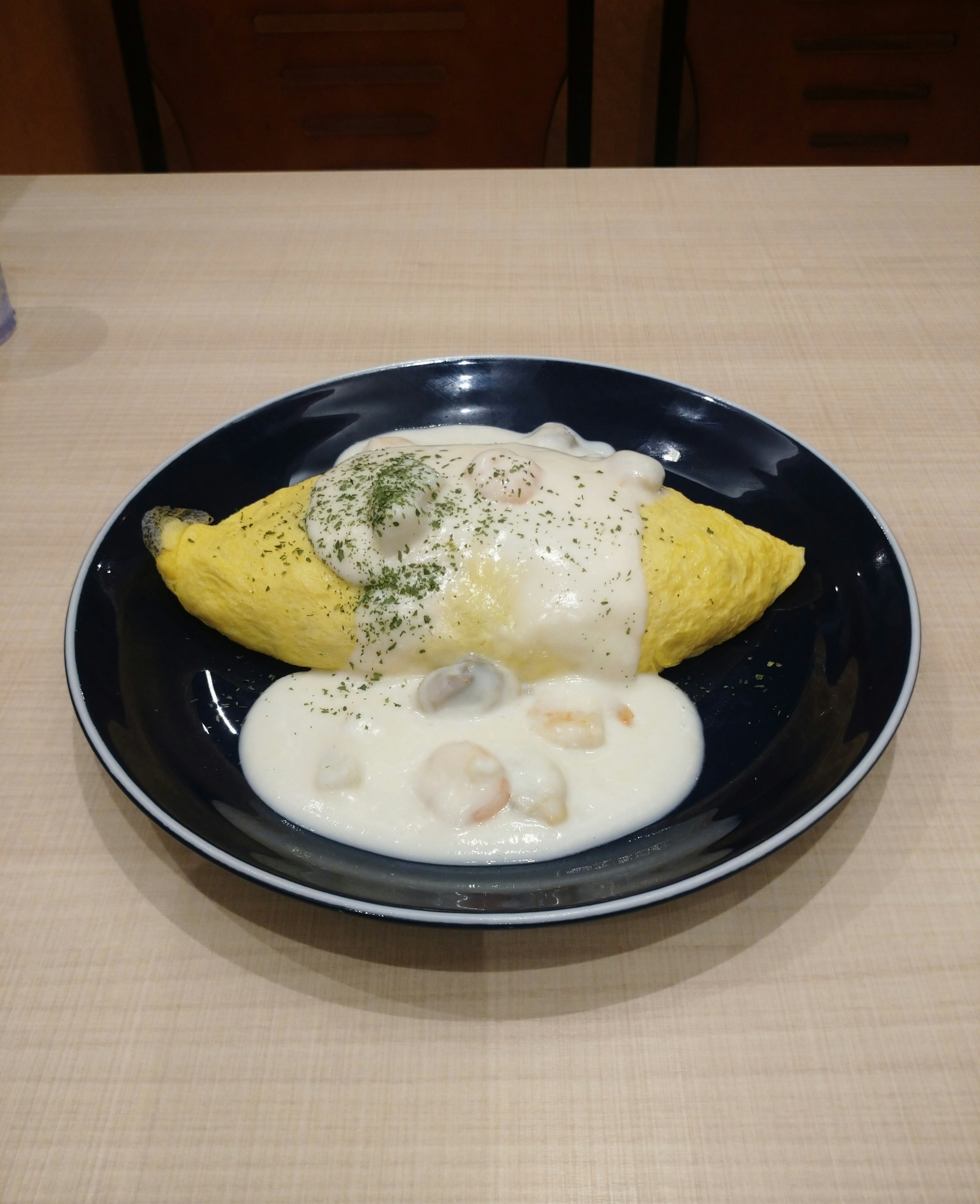 Omelet covered in creamy white sauce served with shrimp on the side