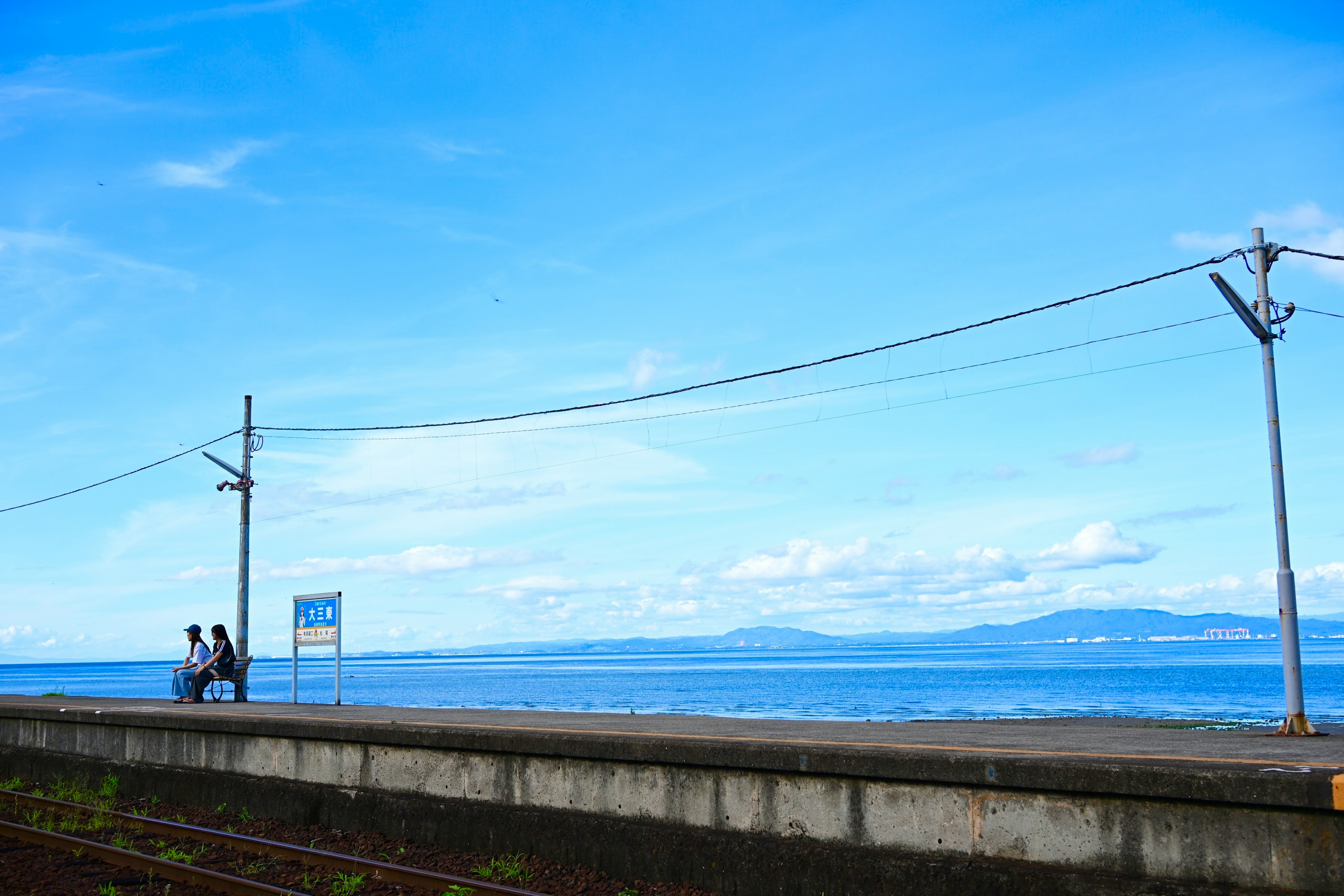 青い空と海が広がる風景に沿って歩く人々