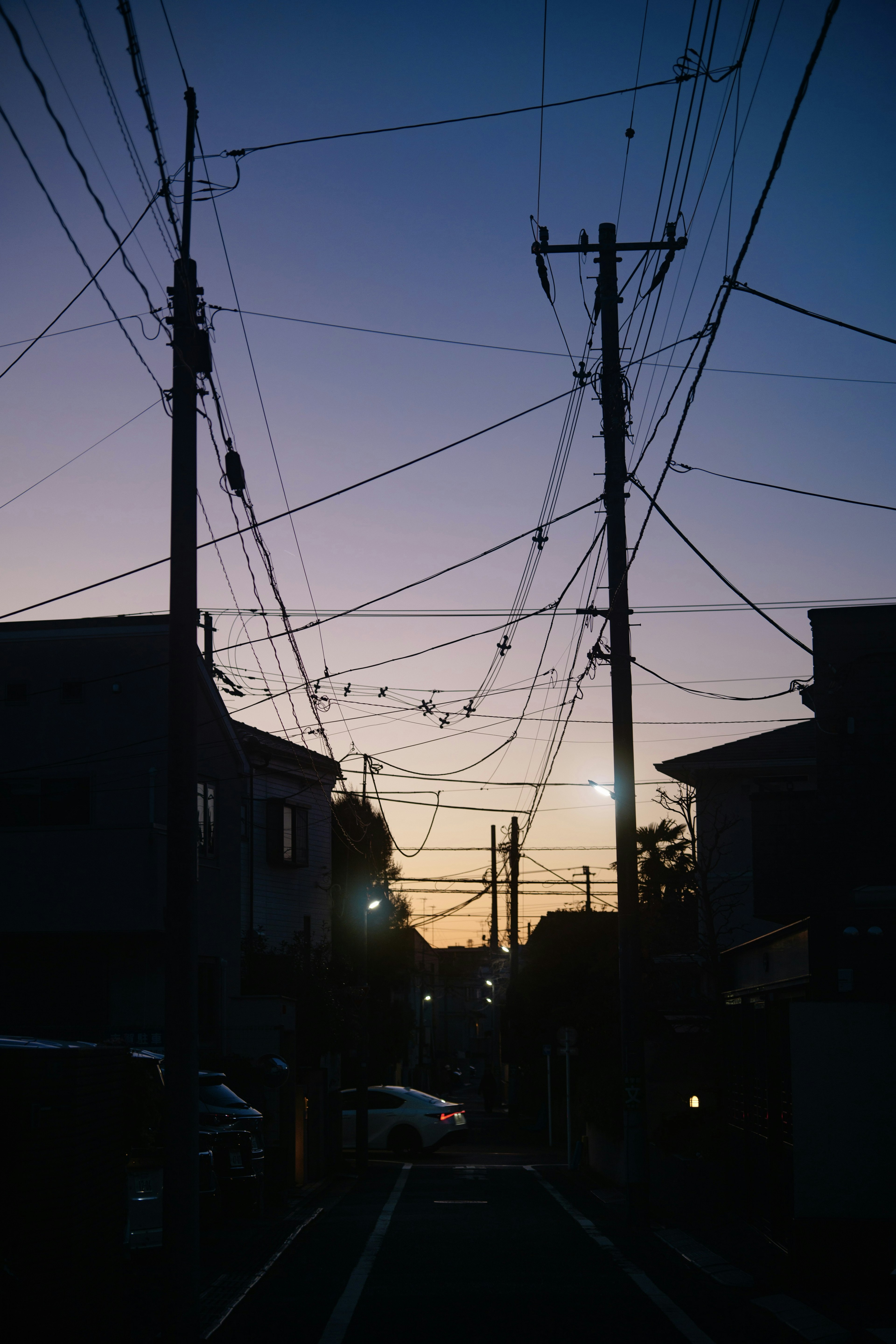 Silueta de una calle de la ciudad al anochecer con líneas eléctricas cruzadas