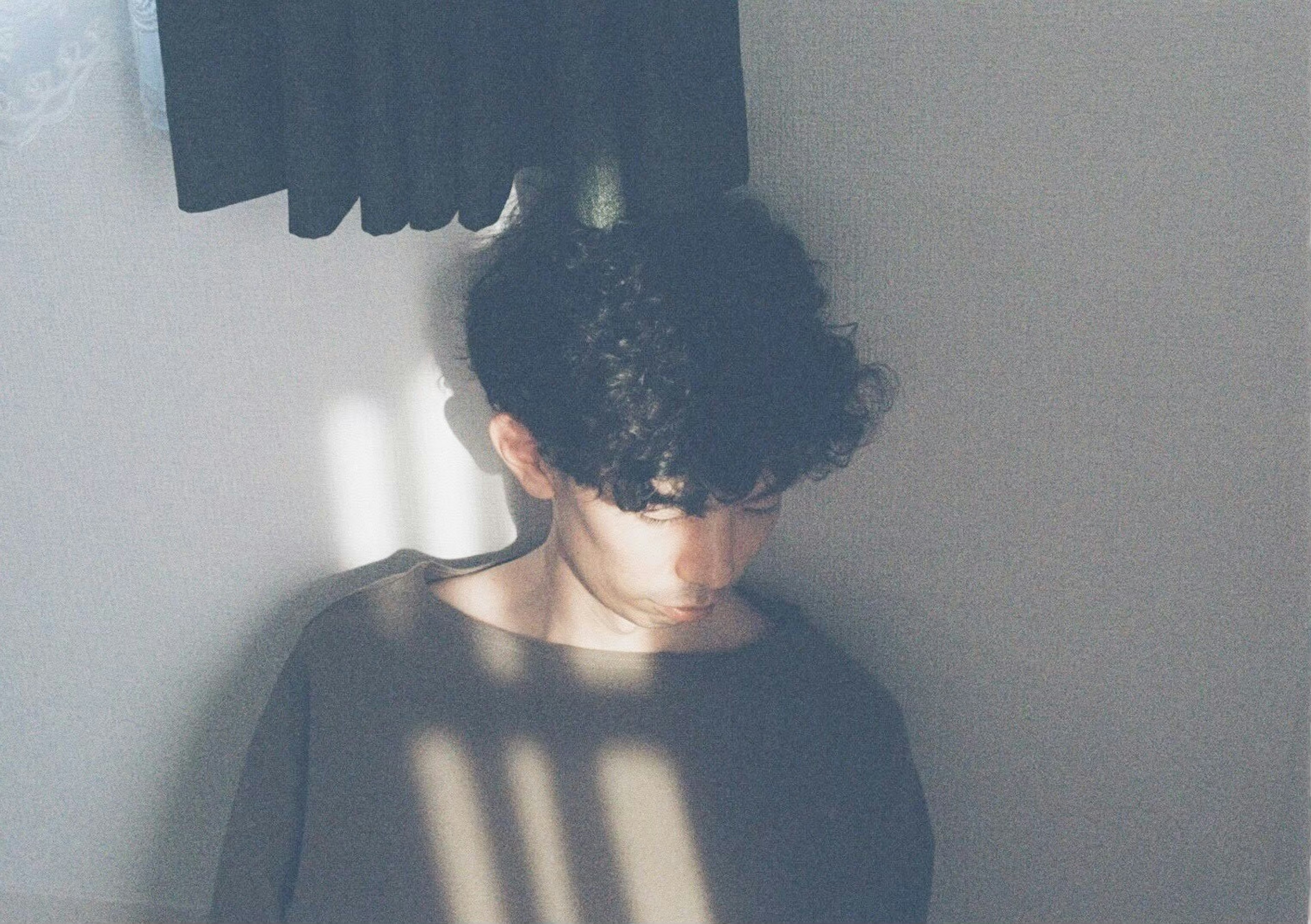 Retrato de un hombre con cabello rizado mirando hacia abajo en una luz suave