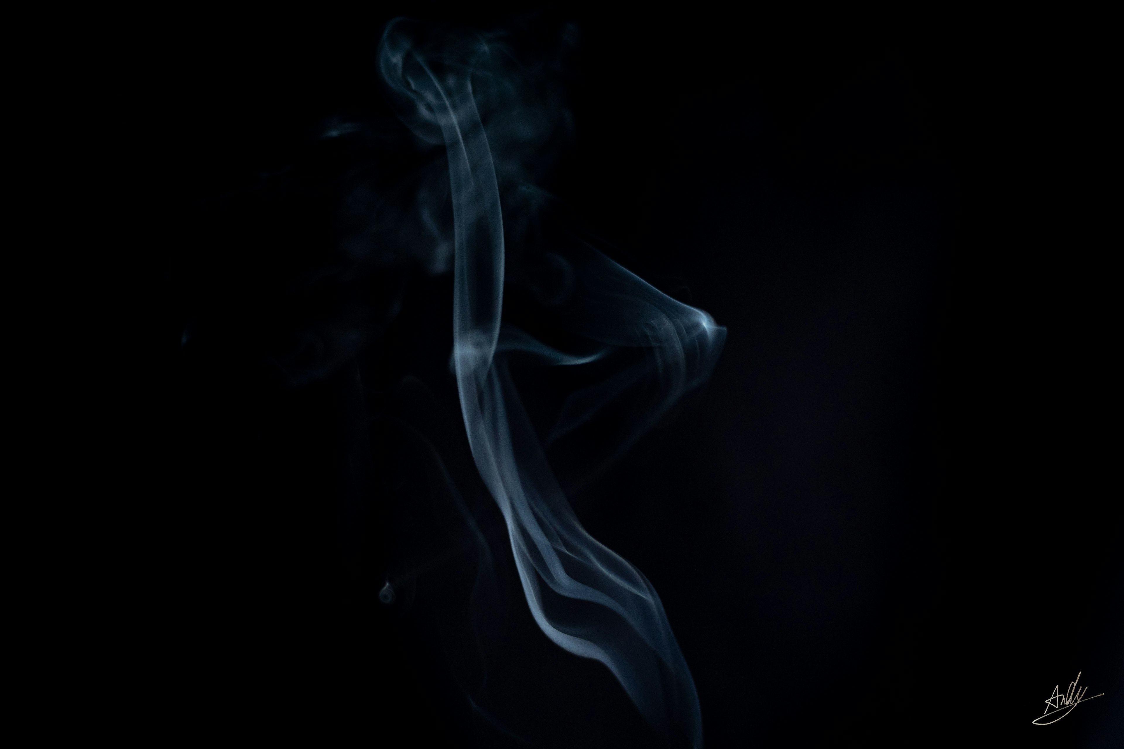 Thin wisps of smoke against a black background