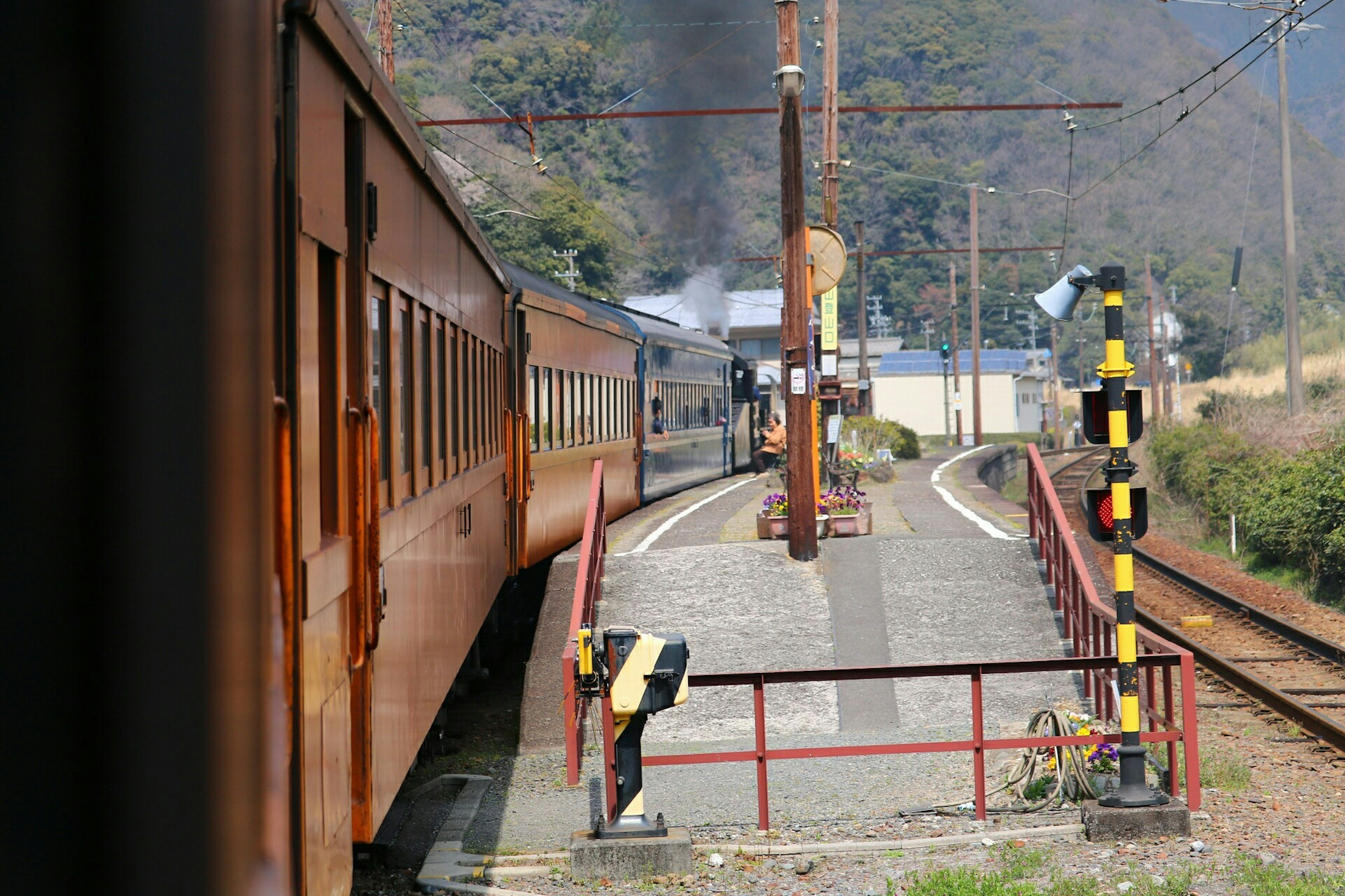 Vista de un tren en una estación con plataforma y señales visibles