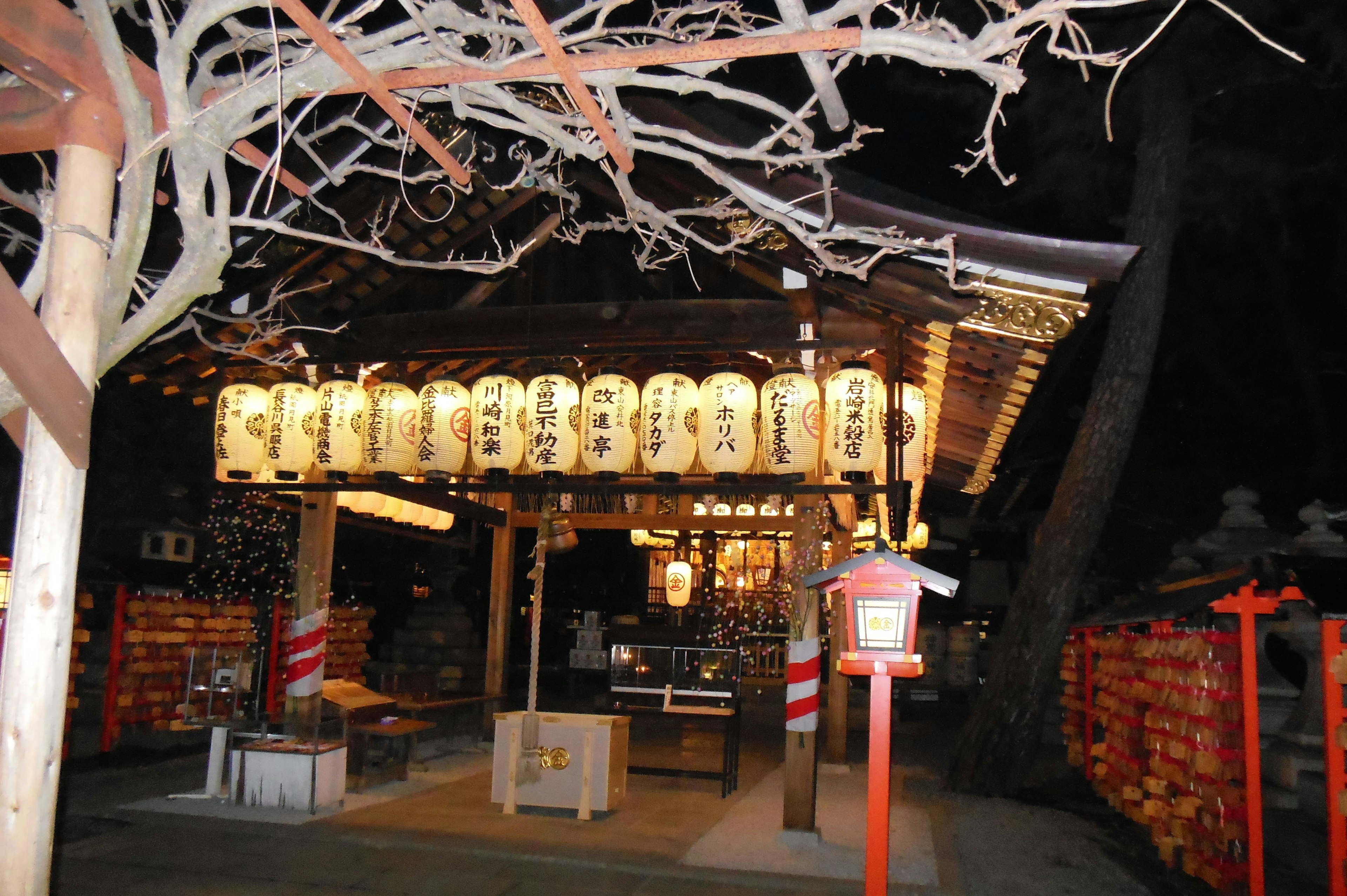 Night view of a shrine featuring illuminated lanterns and wooden structure