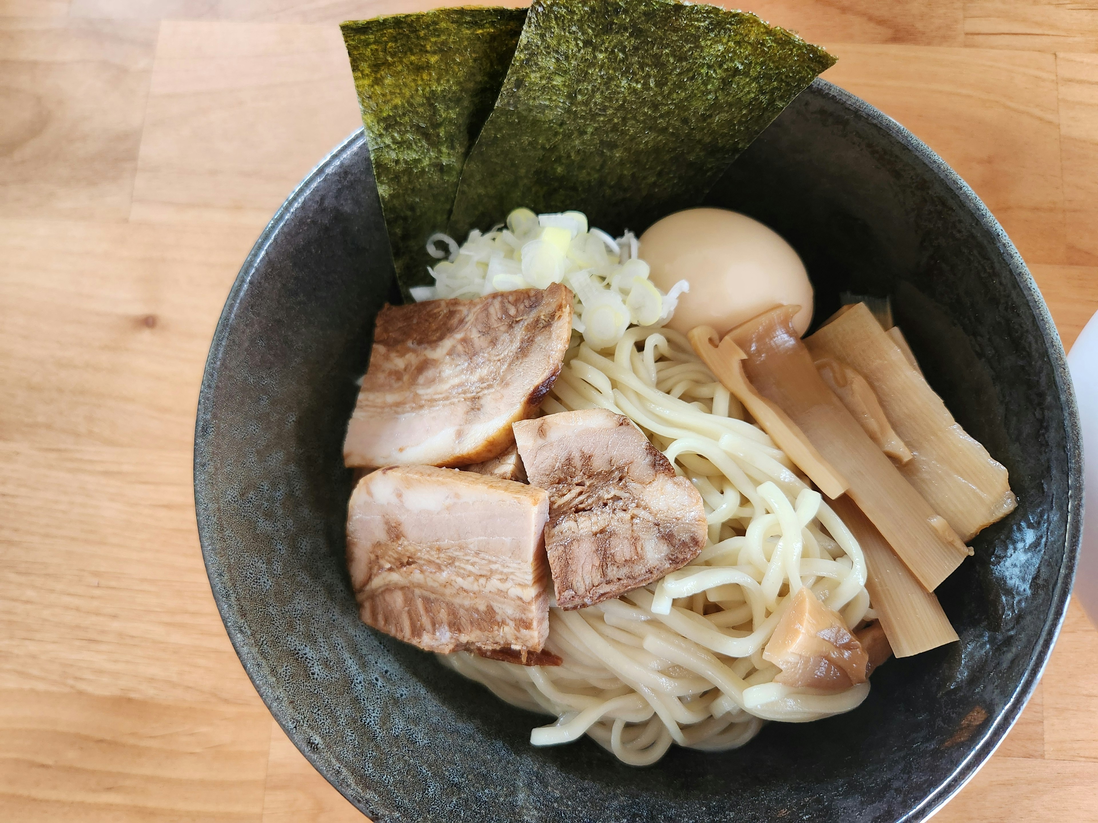 맛있는 라면 그릇, 얇게 썬 돼지고기, 죽순, 반숙 계란, 해조류, 파가 얹혀 있음