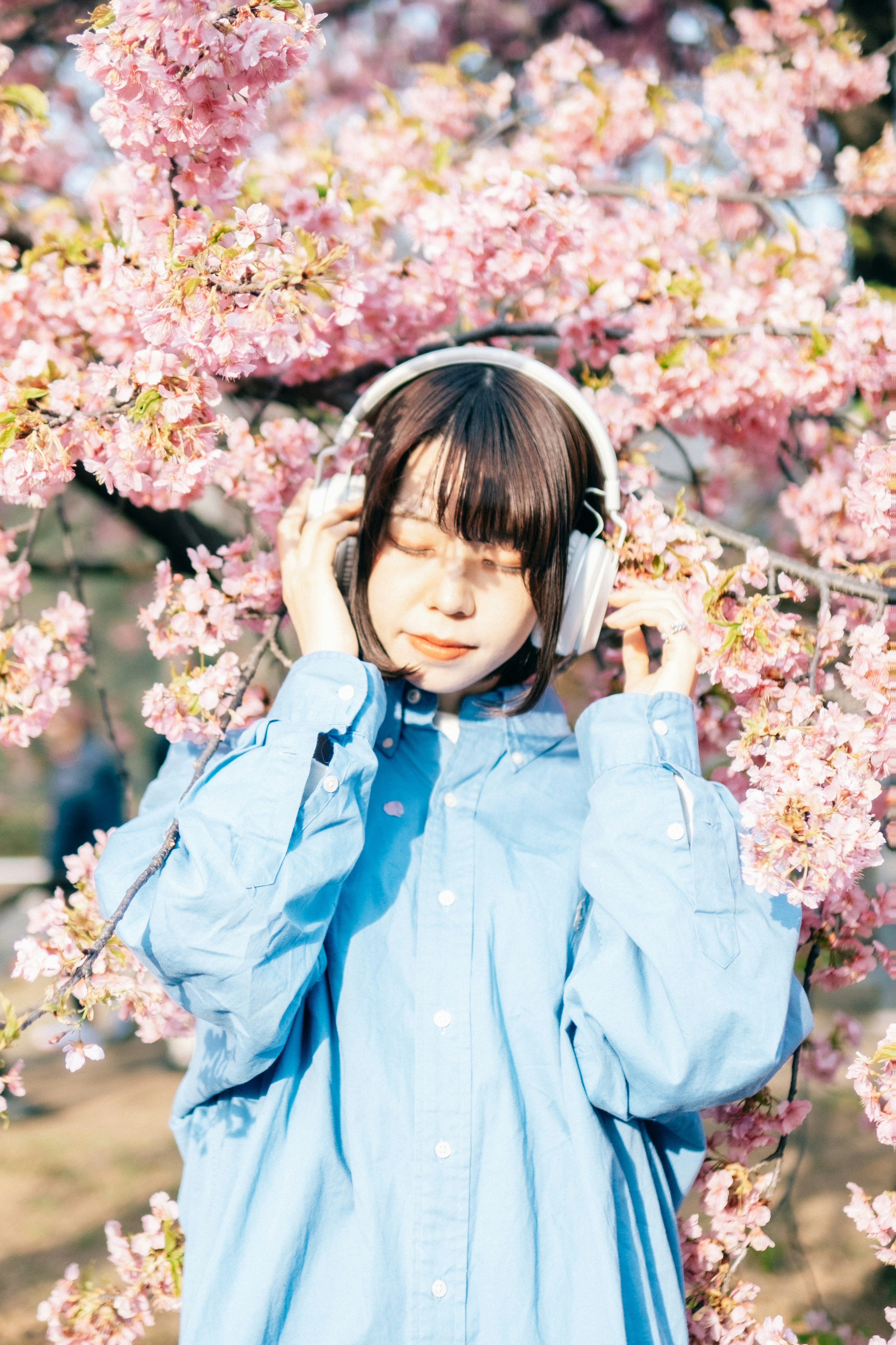 Chica con auriculares frente a cerezos en flor