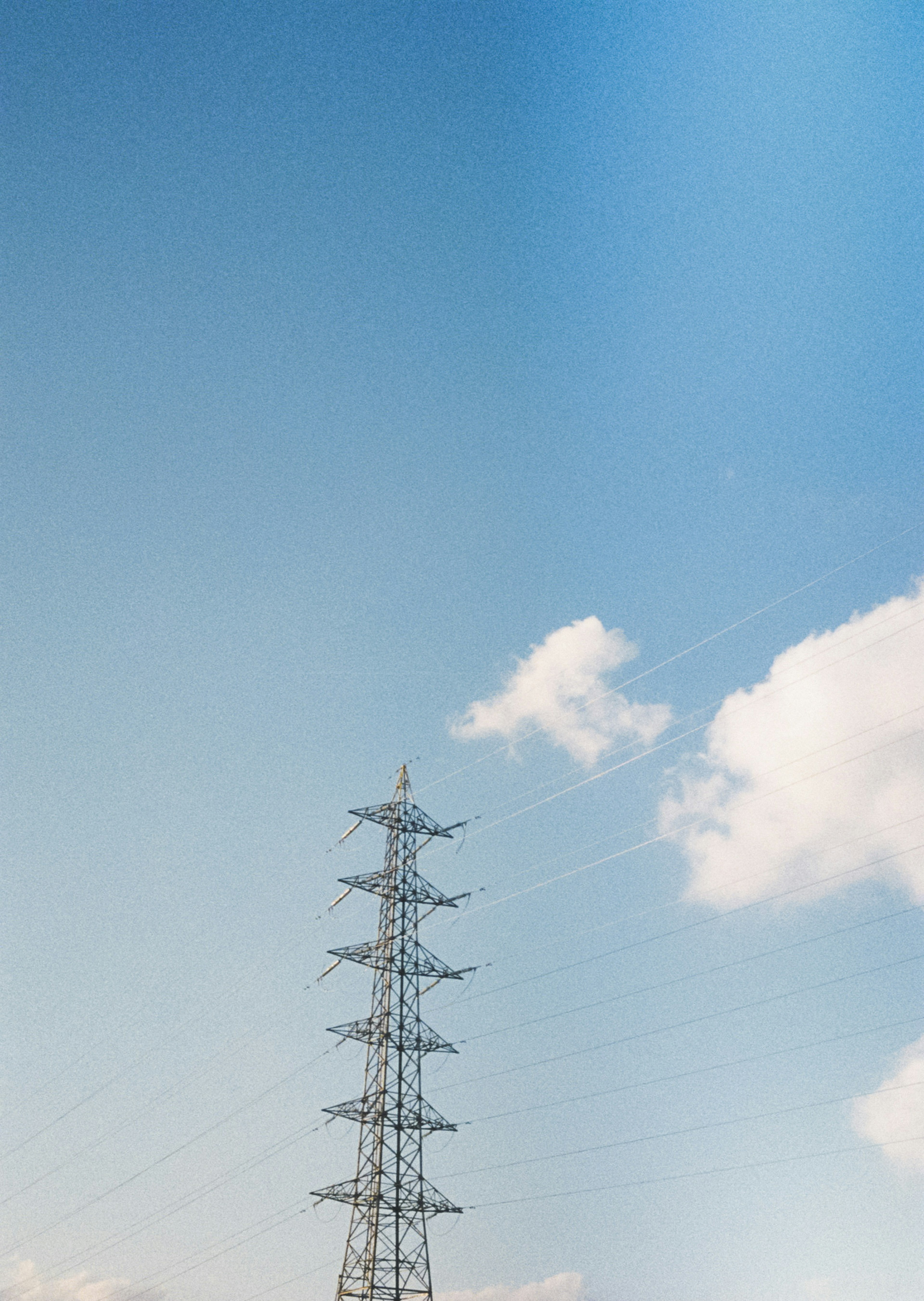 Silhouette of a power tower against a clear blue sky